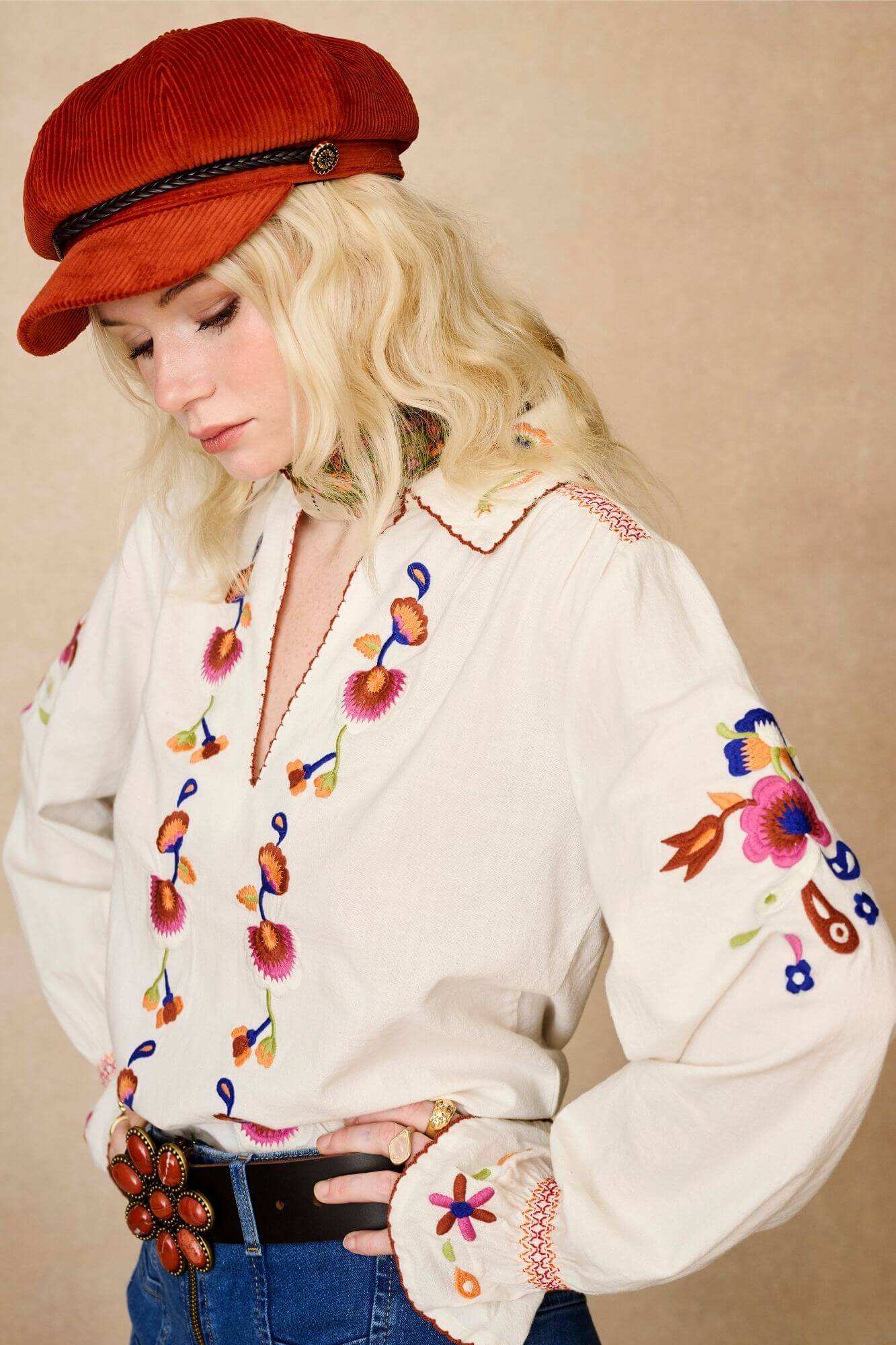 Model wears cream embroidered blouse in textured cotton with floral detailing and balloon sleeves. A 70s-inspired boho blouse made for everyday vintage styling by The Hippie Shake