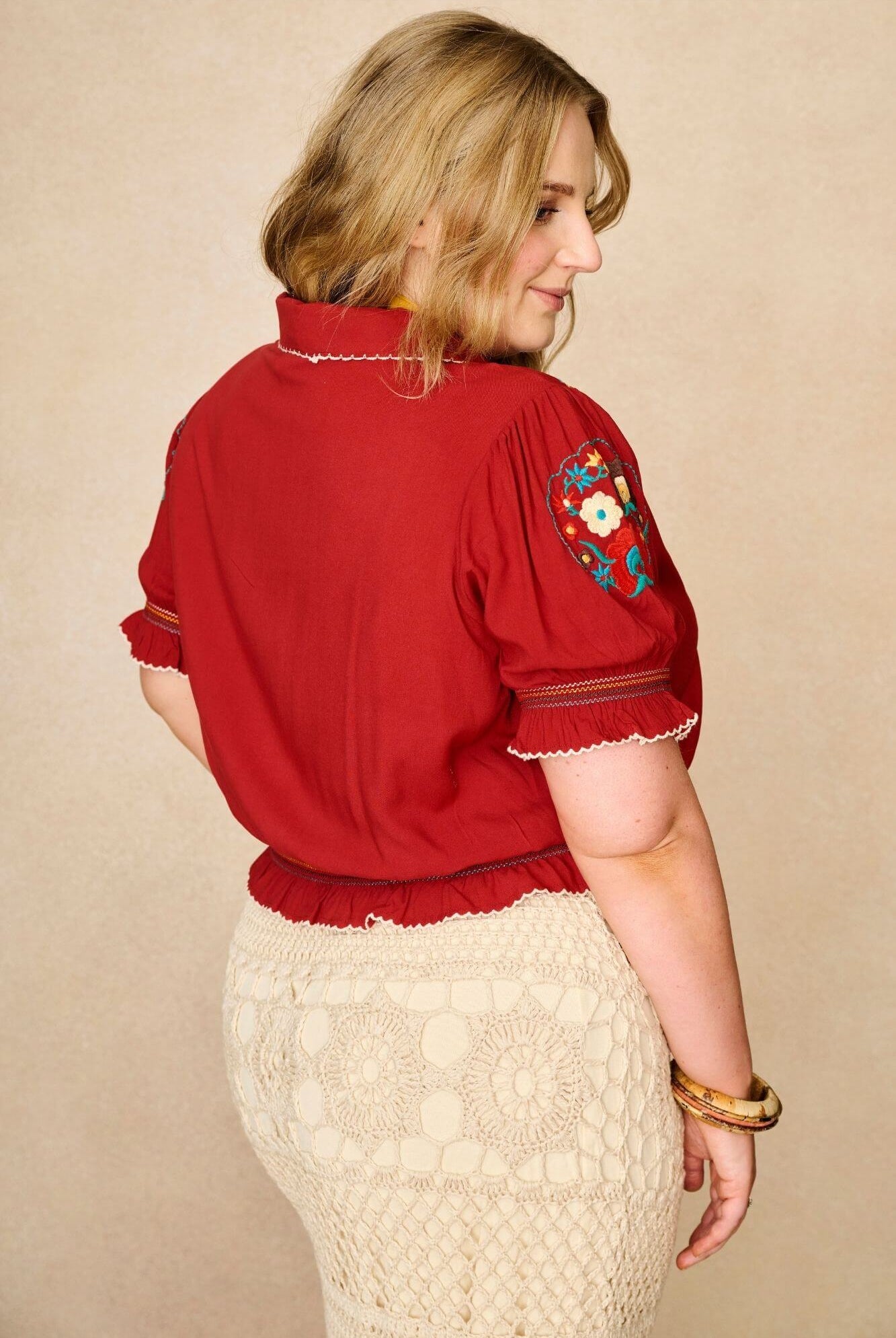 Model wears red floral embroidered Penny Lane blouse in soft cotton with shirred details. A vintage-inspired boho blouse made for everyday and festival styling by The Hippie Shake. Back view