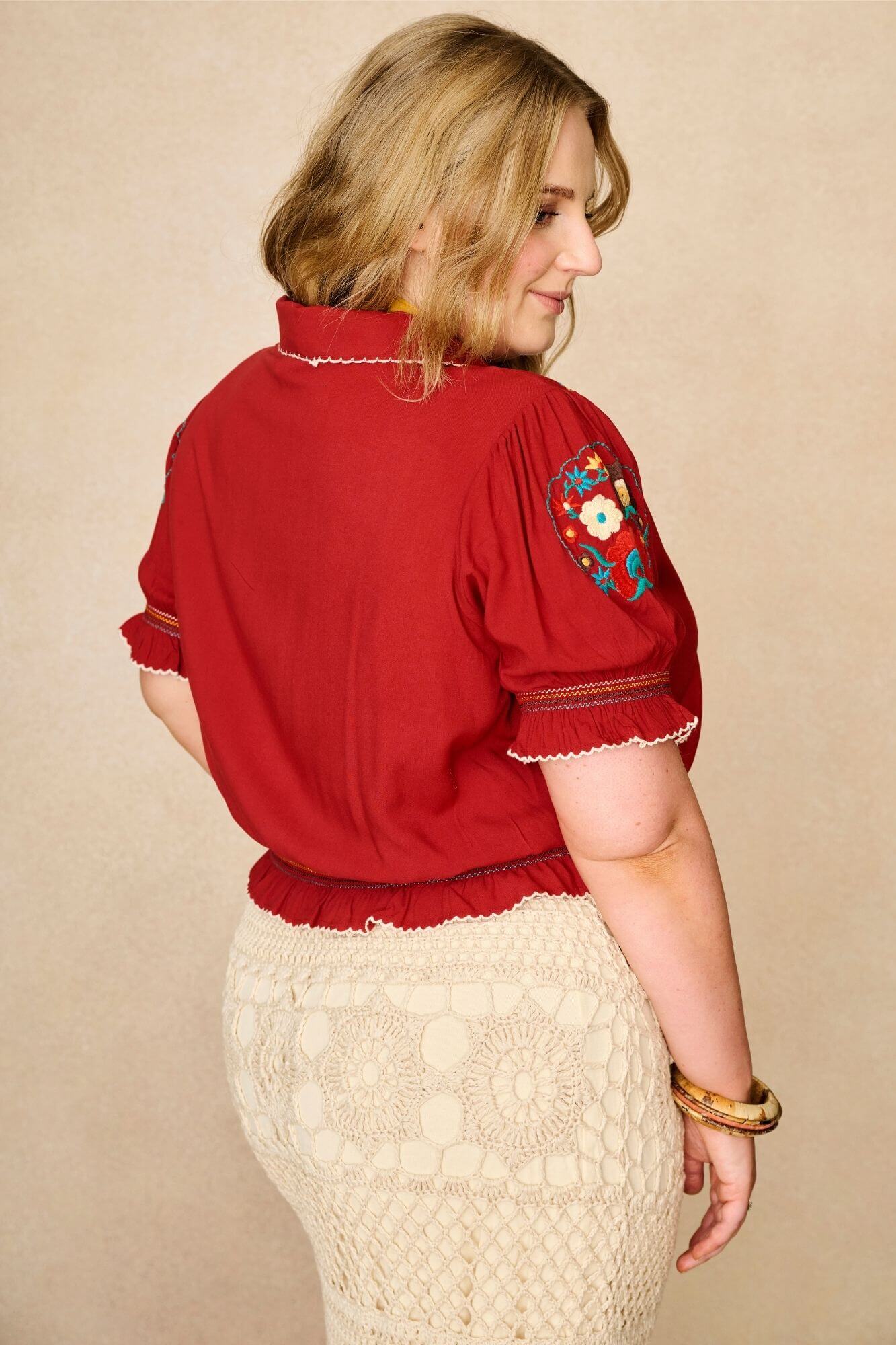 Model wears red floral embroidered Penny Lane blouse in soft cotton with shirred details. A vintage-inspired boho blouse made for everyday and festival styling by The Hippie Shake. Back view