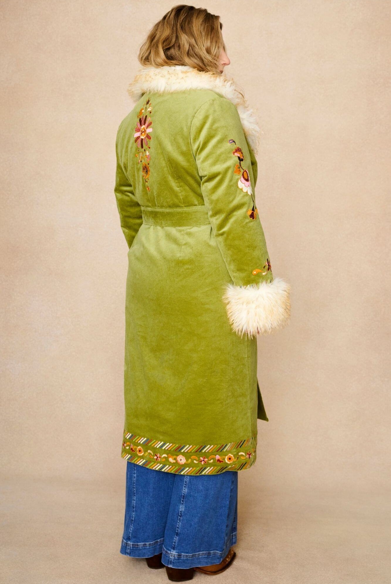 Model wears green embroidered Penny Lane coat in cotton corduroy with faux fur trim. A 70s-inspired statement coat made for bohemian, vintage styling by The Hippie Shake - back view