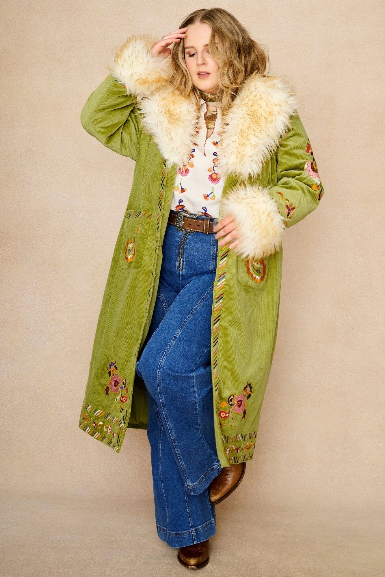 Model wears green embroidered Penny Lane coat in cotton corduroy with faux fur trim. A 70s-inspired statement coat made for bohemian, vintage styling by The Hippie Shake - open front view