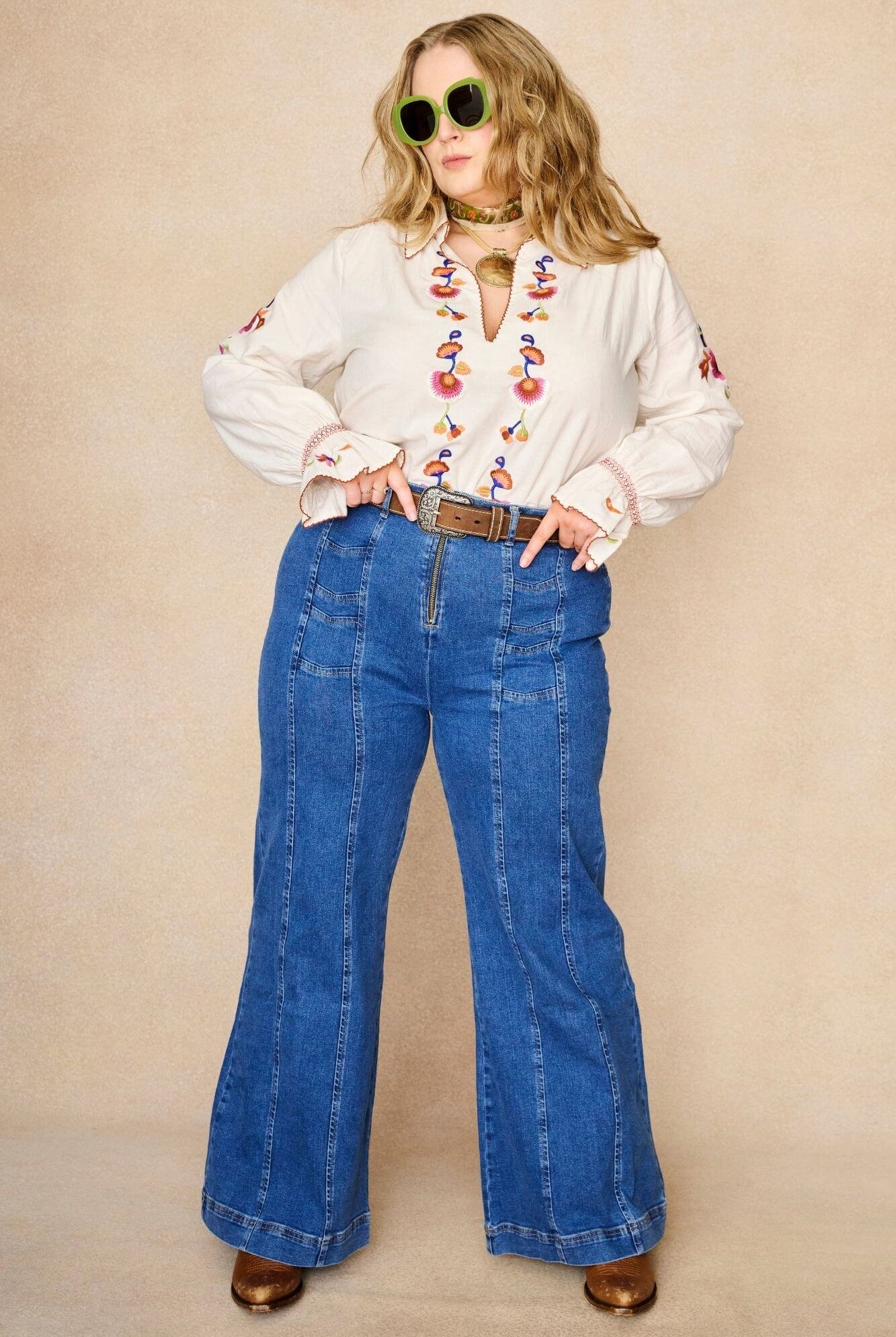Model wears cream embroidered blouse in textured cotton with floral detailing and balloon sleeves paired with flared denim jeans. A 70s-inspired boho blouse made for everyday vintage styling by The Hippie Shake - standing front view