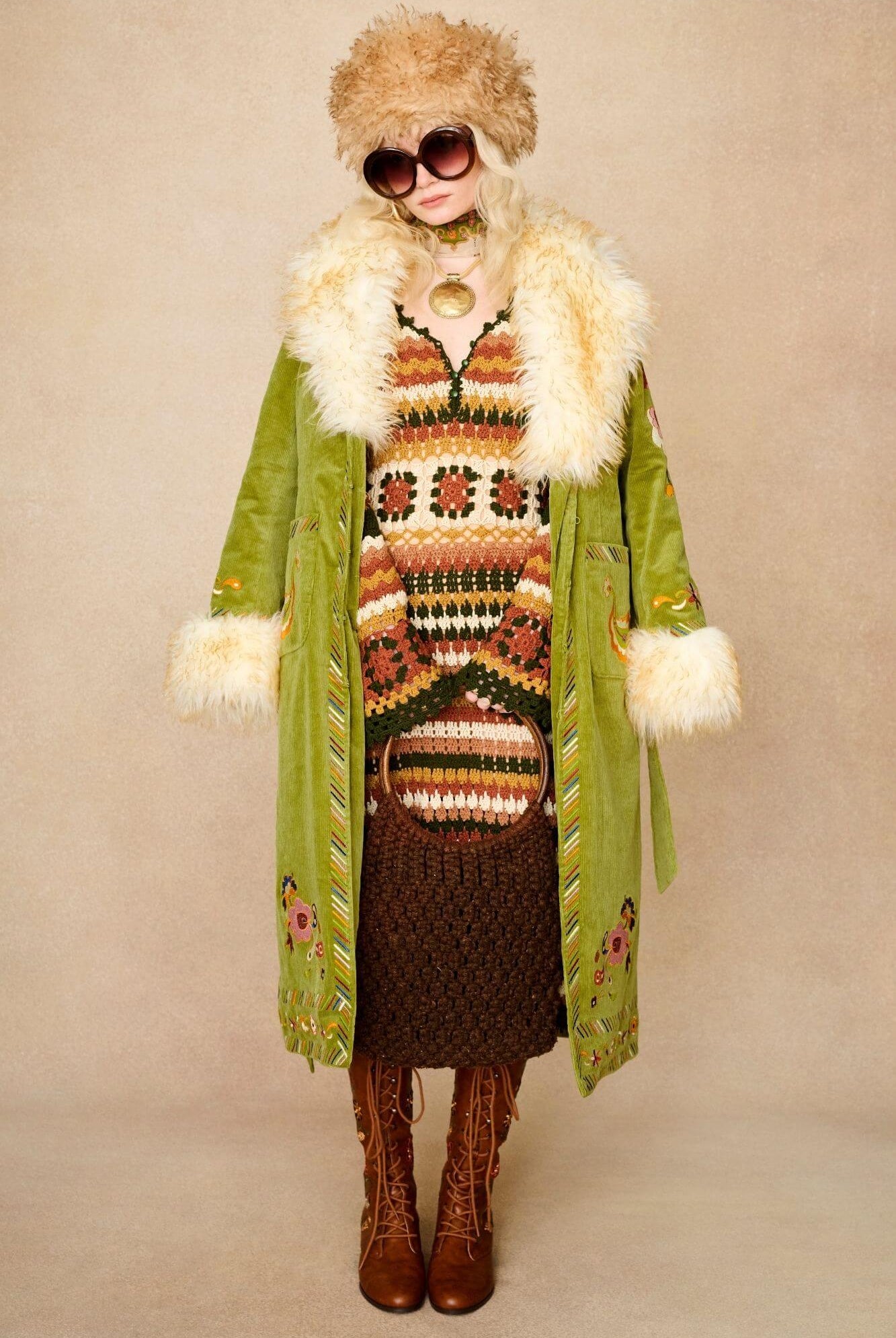 Model wears green embroidered Penny Lane coat in cotton corduroy with faux fur trim. A 70s-inspired statement coat made for bohemian, vintage styling by The Hippie Shake - paired with crochet midi dress