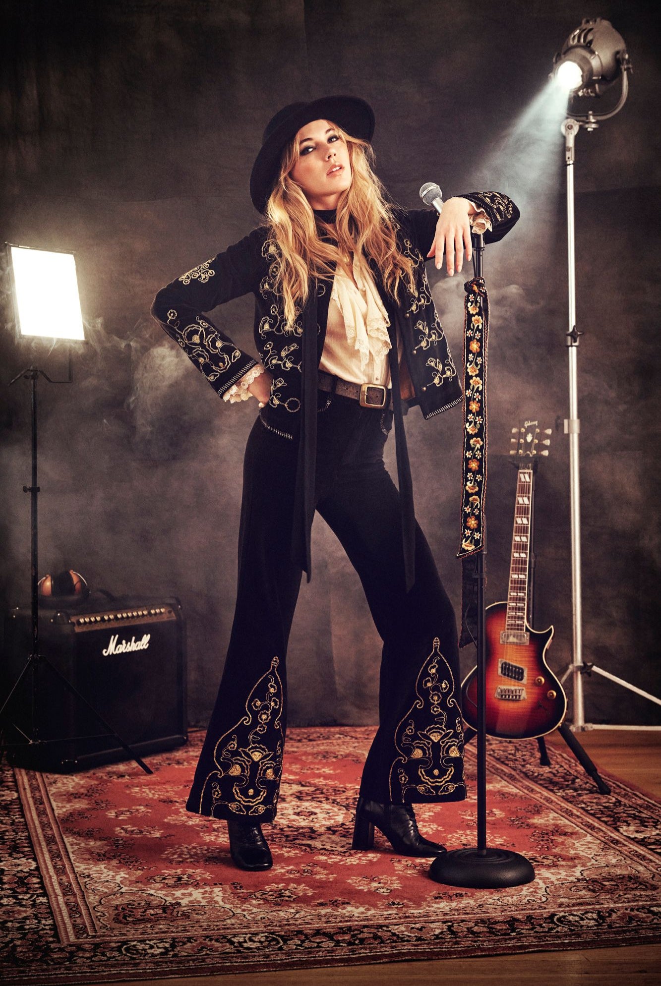 The Hippie Shake paint it black collection -model wears black velvet suit with gold embroidered embroidery standing with a microphone on stage