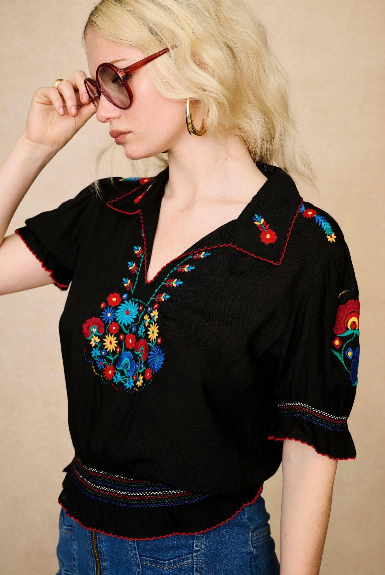 Model wears black floral embroidered blouse in soft cotton with shirred details. A vintage-inspired Penny Lane blouse made for boho, festival and everyday styling by The Hippie Shake - side view