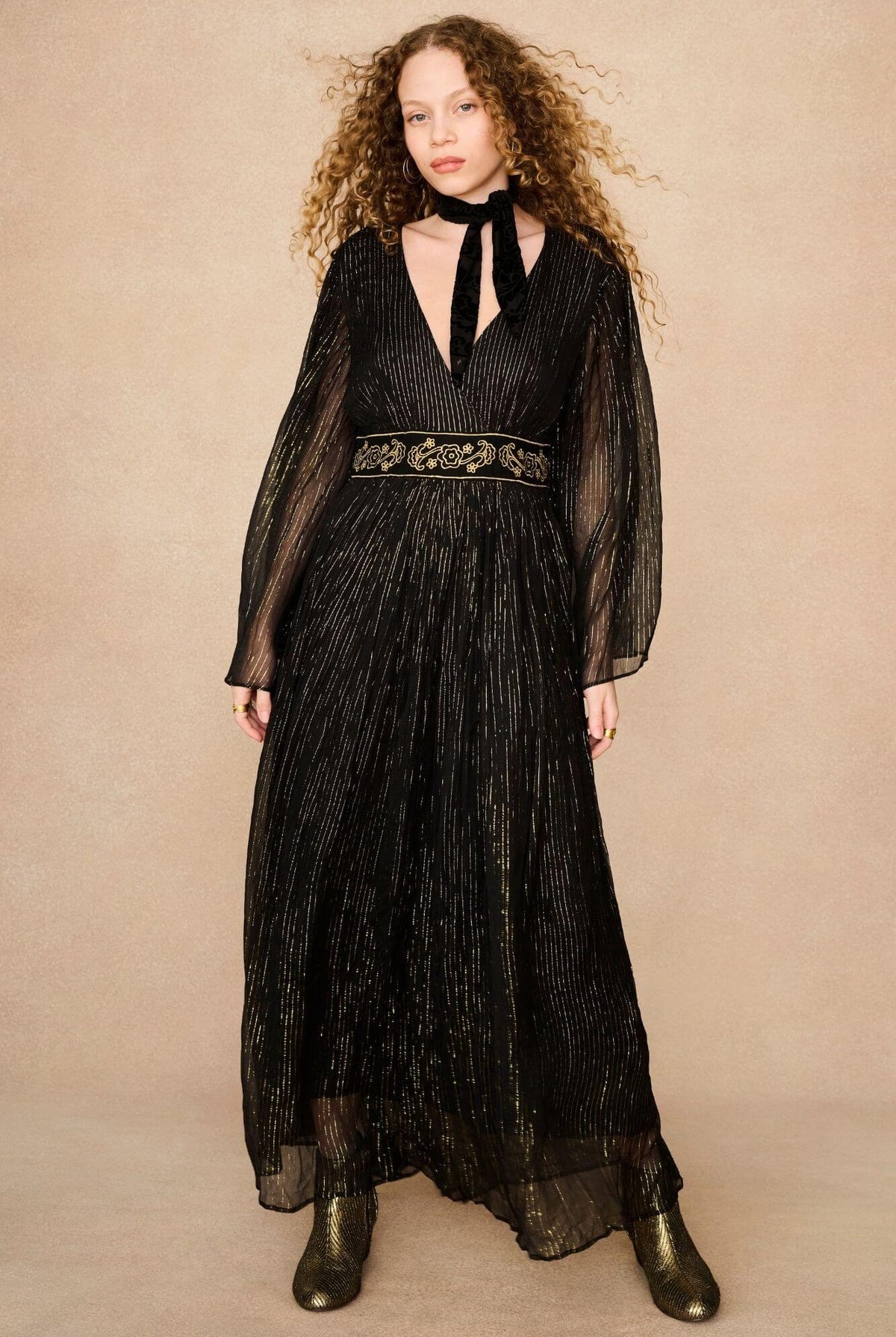 A model wearing a black maxi dress with sheer long flowy sleeves by the Hippie Shake