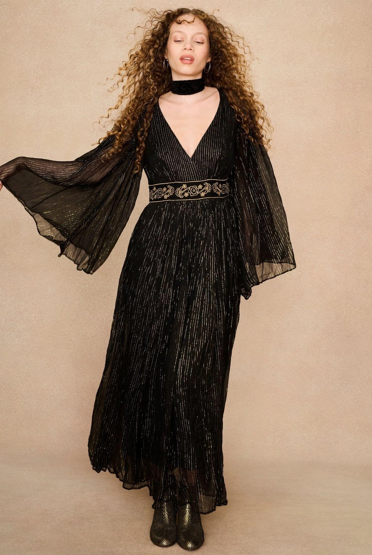 A model wearing a black maxi dress with sheer long flowy sleeves by the Hippie Shake