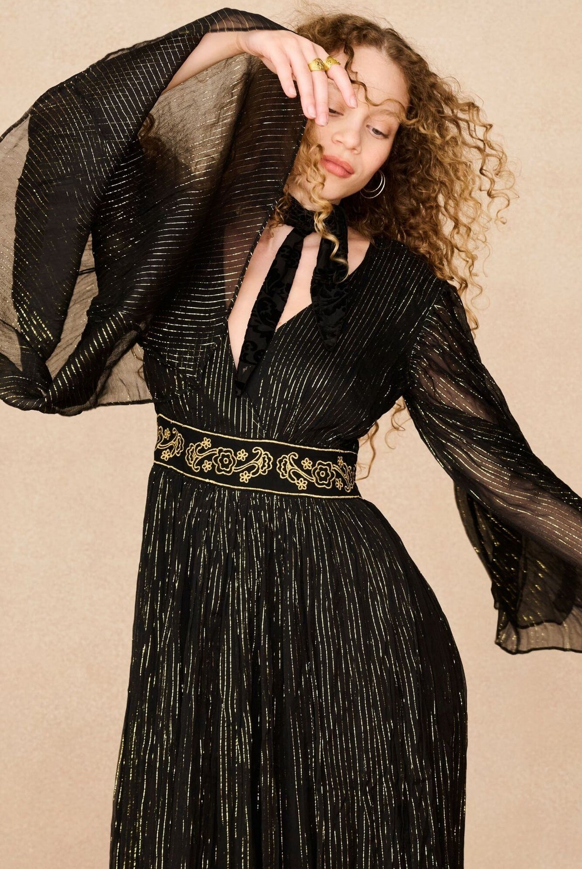 A model wearing a black maxi dress with sheer long flowy sleeves by the Hippie Shake