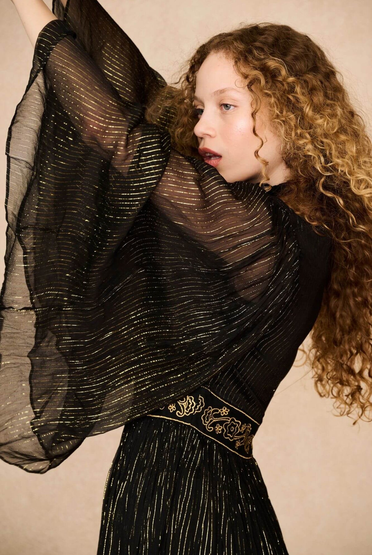 A model wearing a black maxi dress with sheer long flowy sleeves by the Hippie Shake