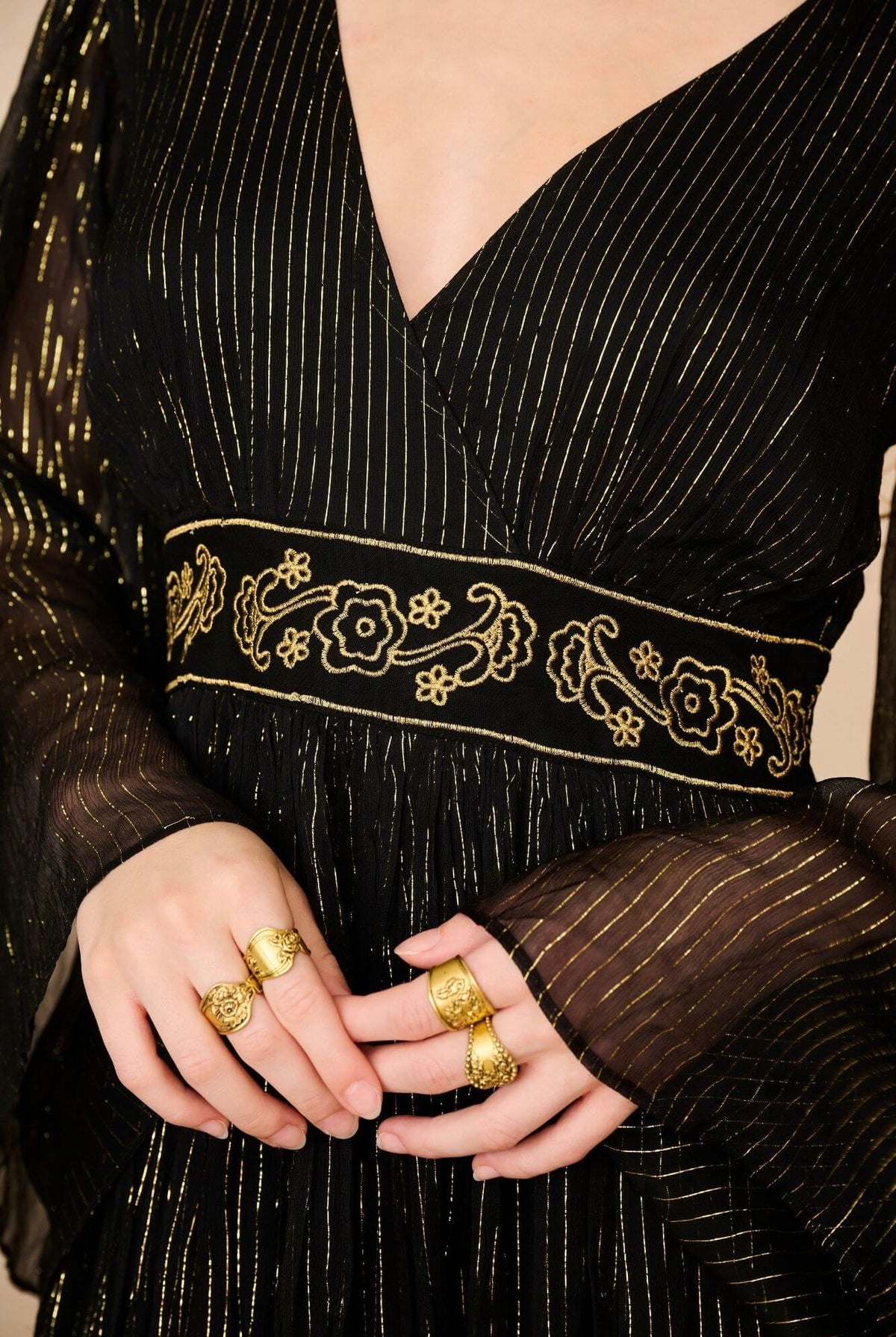 A model wearing a black maxi dress with sheer long flowy sleeves by the Hippie Shake, close up shot