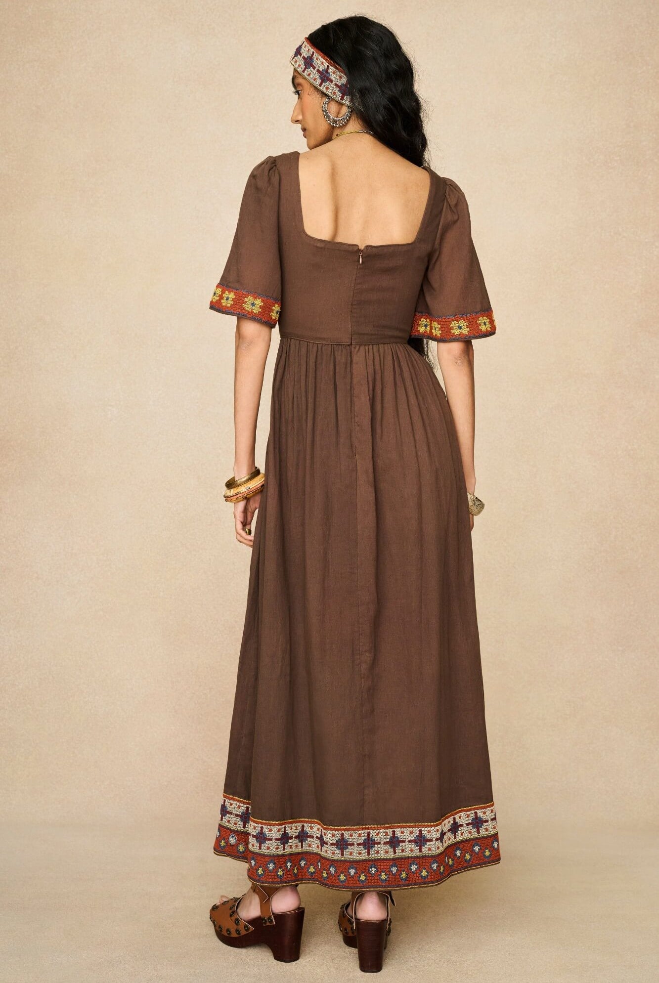 Model wearing brown embroidered maxi dress by The Hippie Shake, back view