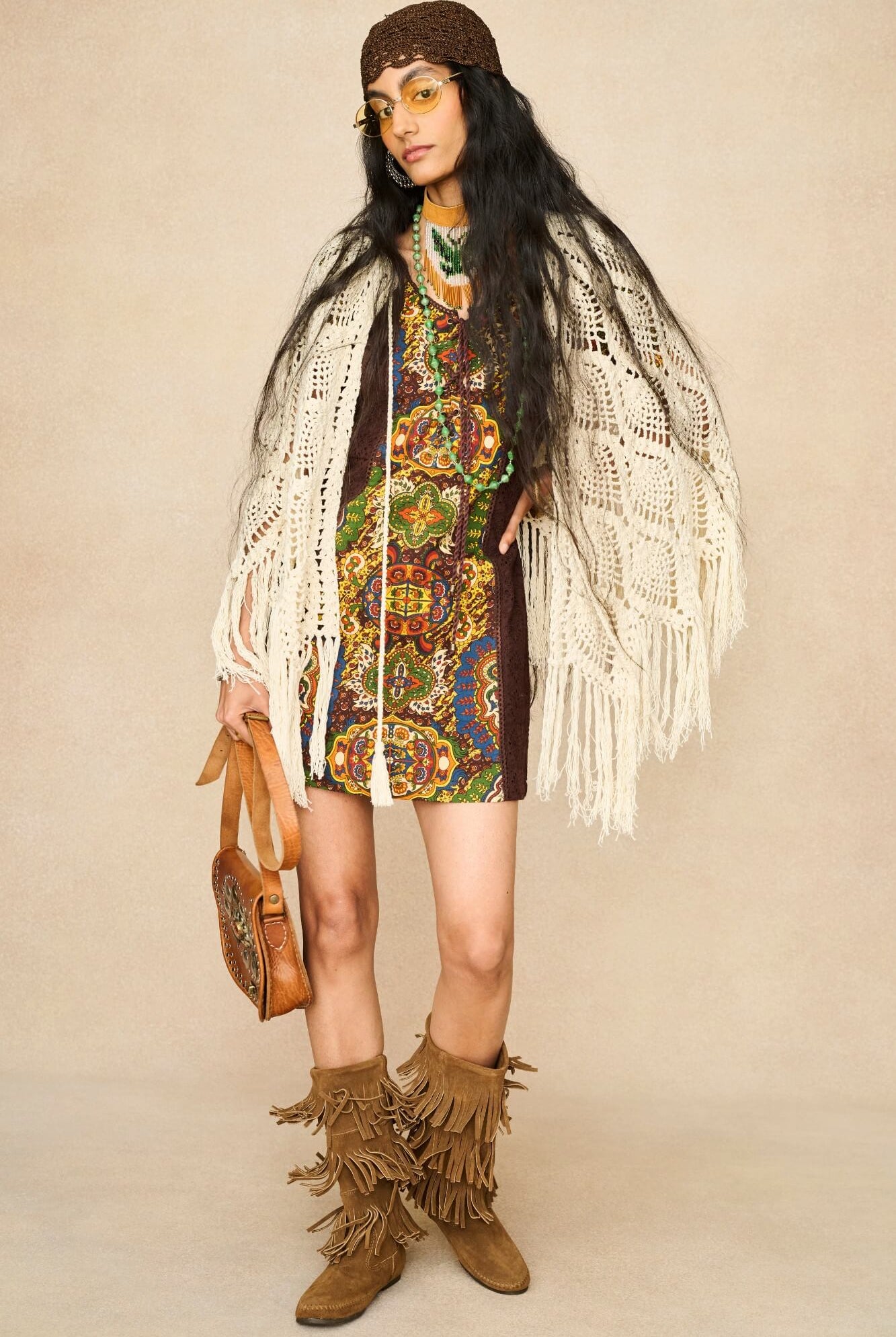 Model wearing cream crochet cape with 70s printed mini dress by The Hippie Shake, front view