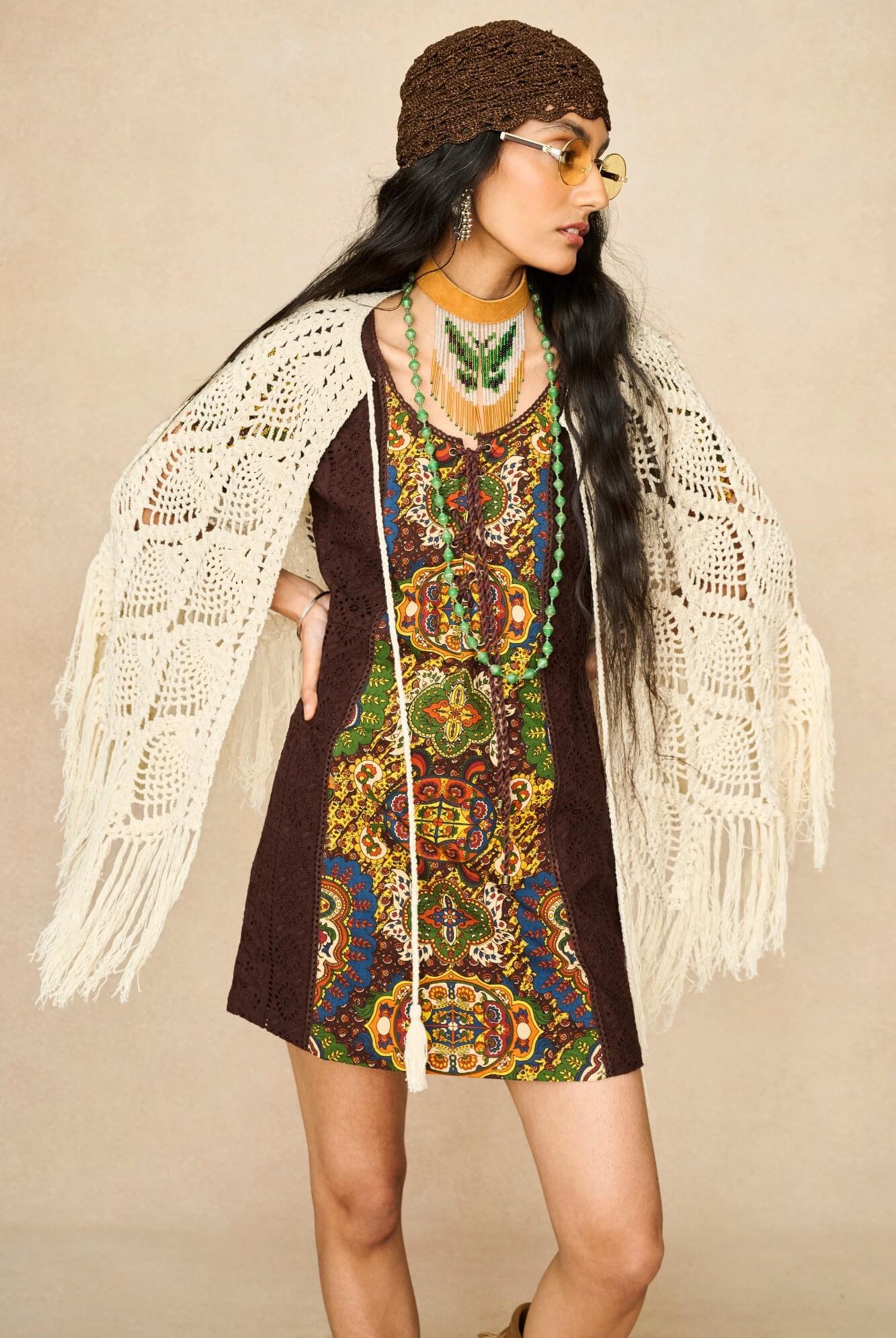 Model wearing cream crochet cape with 70s printed mini dress by The Hippie Shake, front view