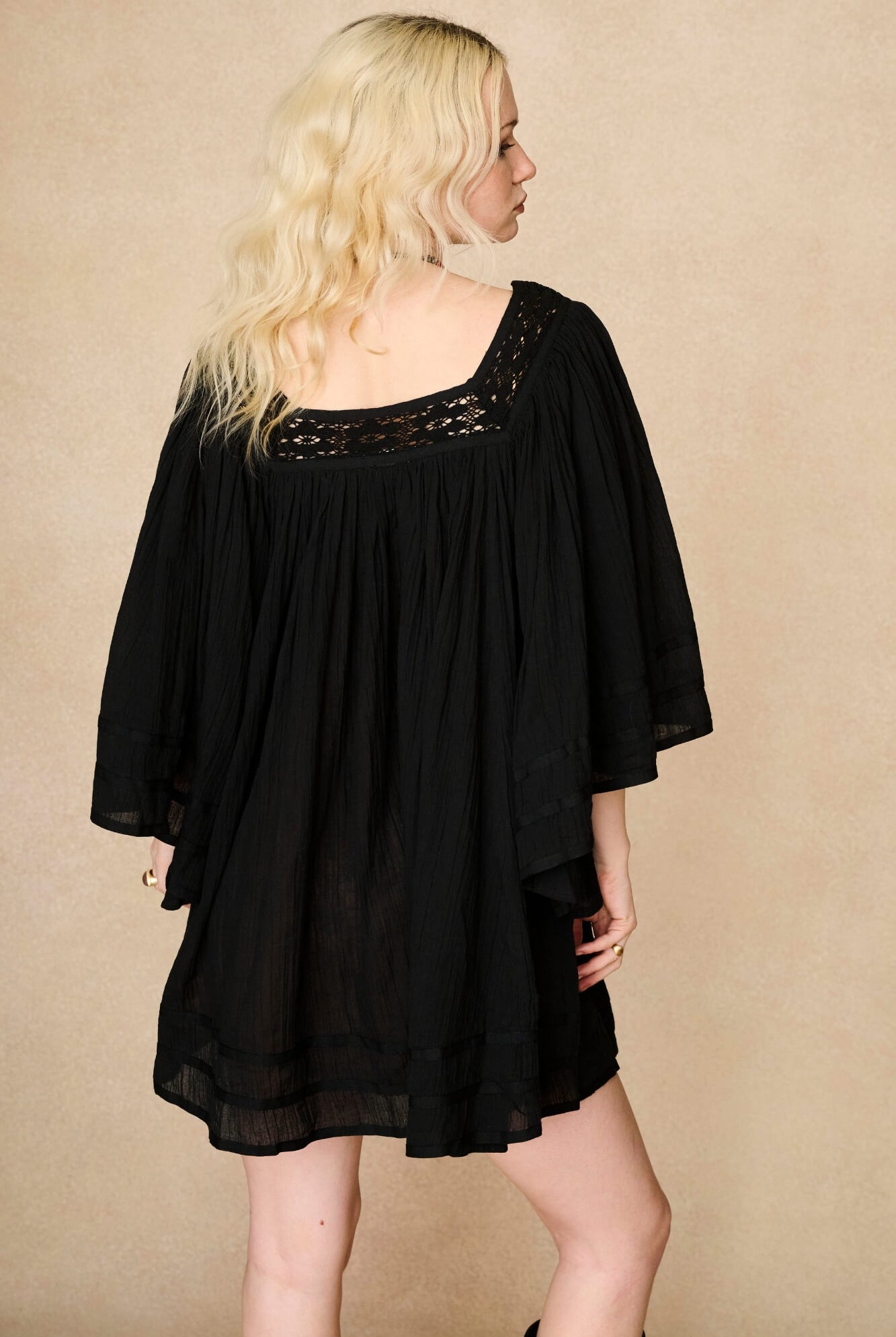 Model wearing 70s black mini dress with lace-up Penny Lane boots by The Hippie Shake, back view