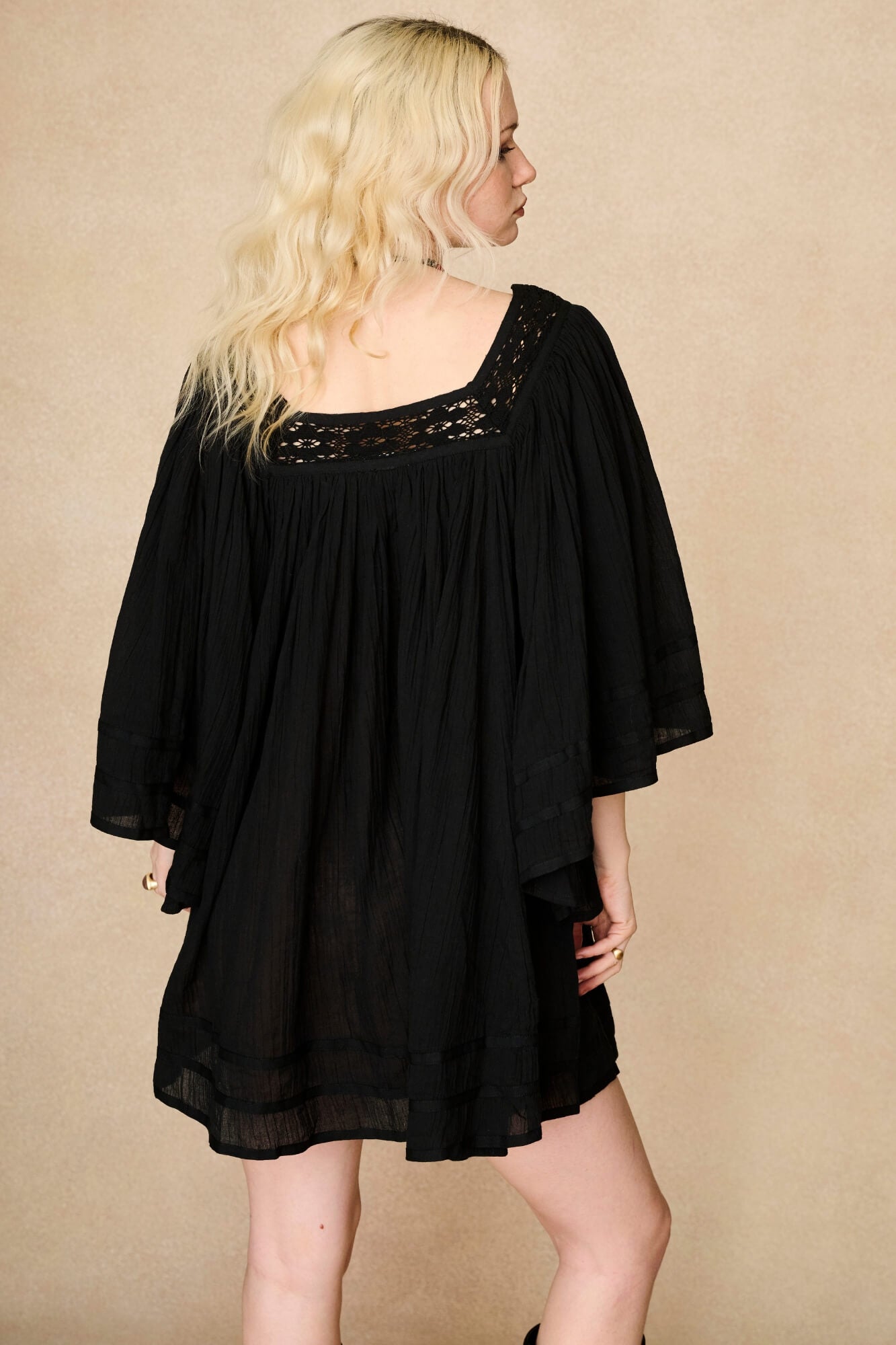 Model wearing 70s black mini dress with lace-up Penny Lane boots by The Hippie Shake, back view