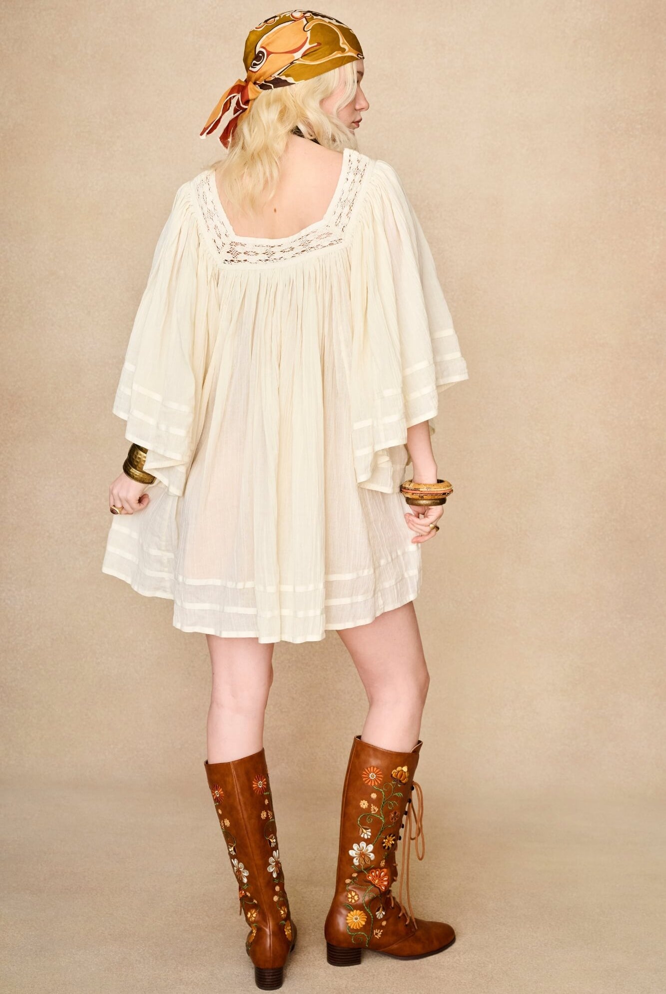 Model wearing 70s cream mini dress with lace-up Penny Lane boots by The Hippie Shake, back view