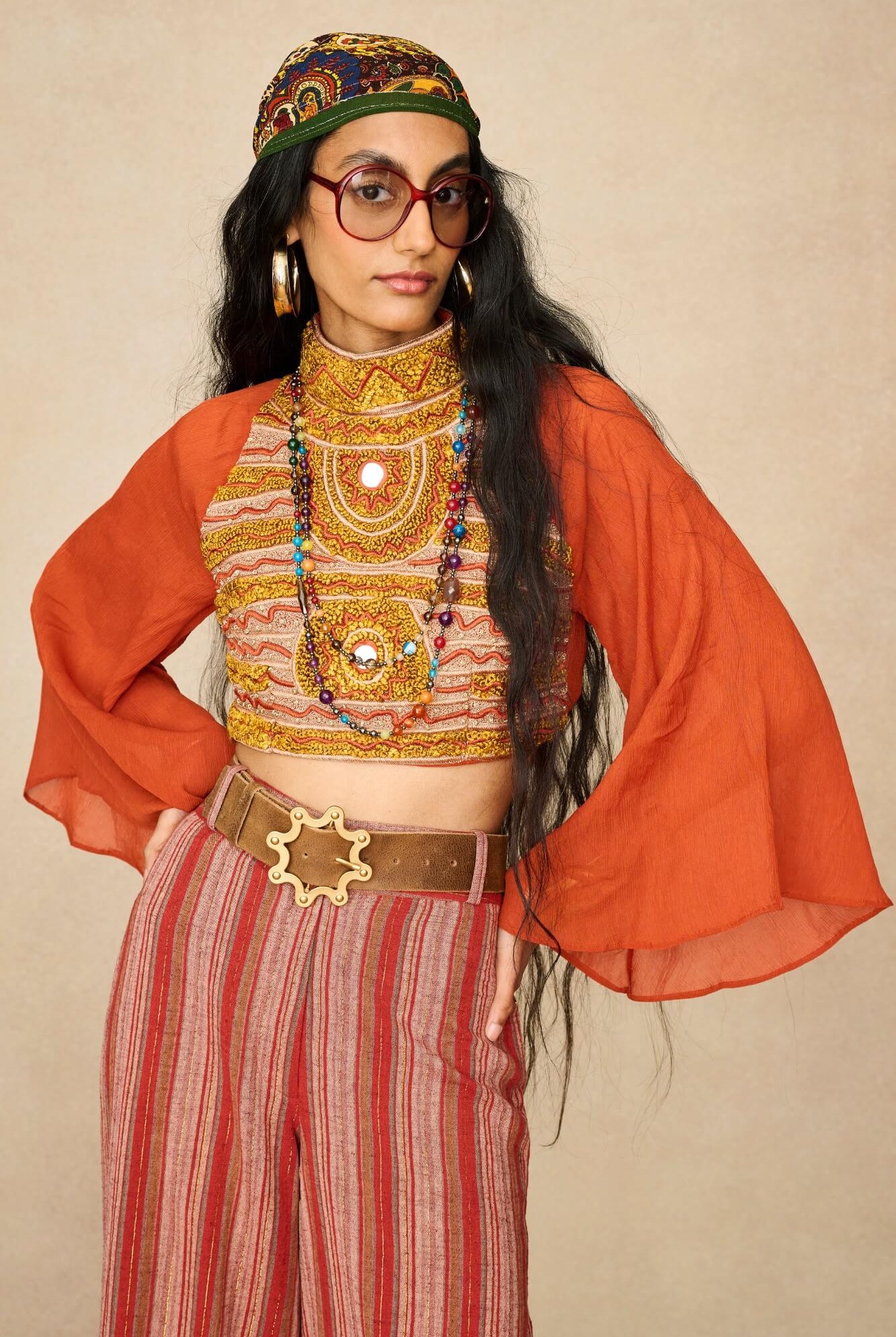 Model wearing 70s orange beaded top with striped trousers by The Hippie Shake, front view
