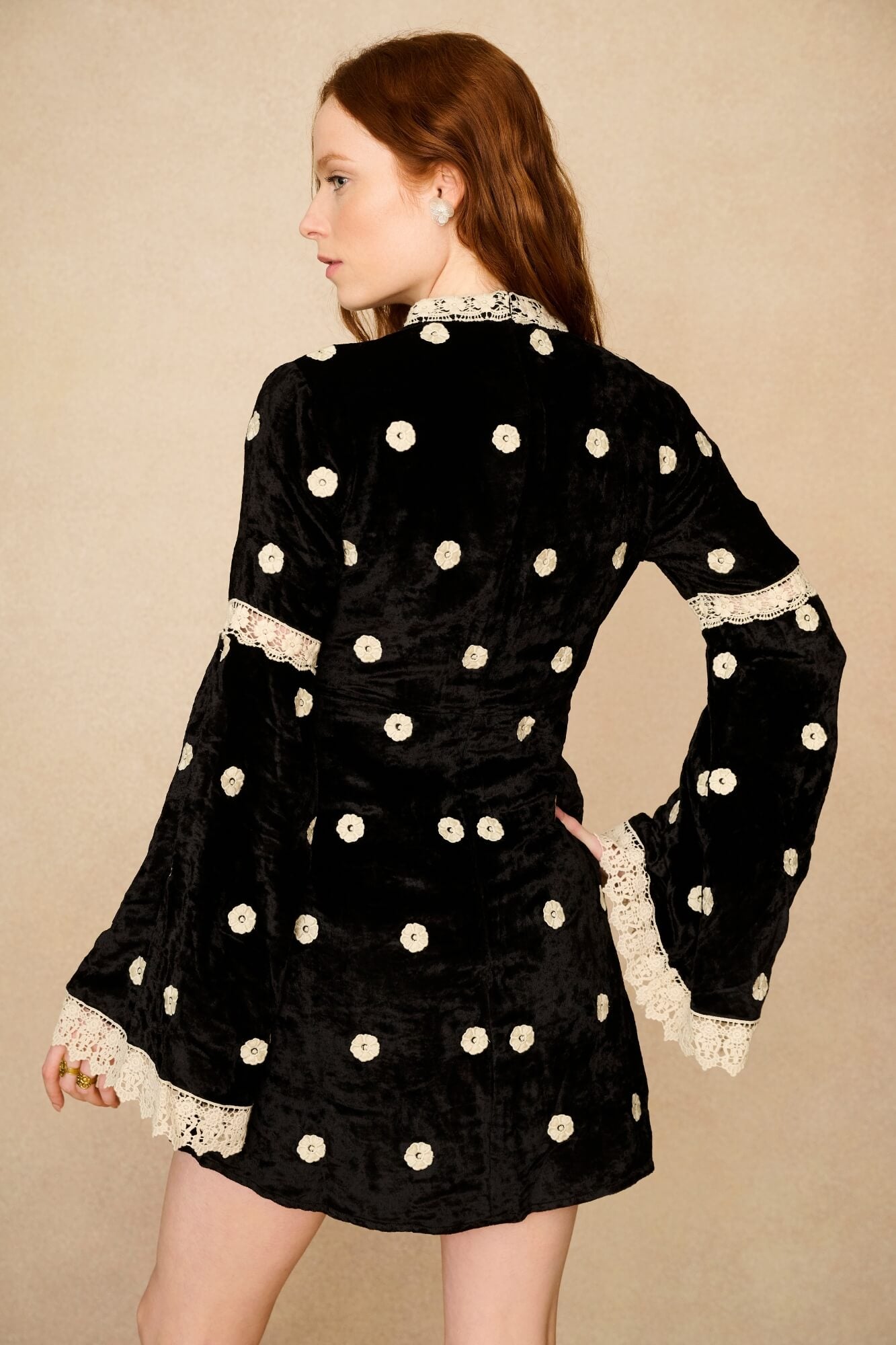 Black dress with white polka dots and lace details on a beige background