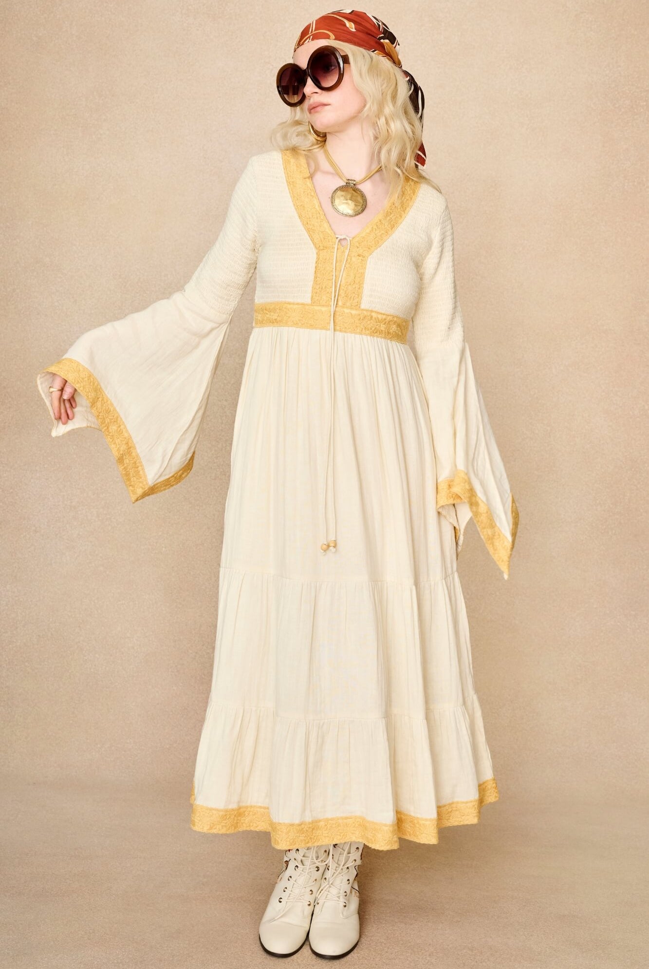Model wearing 70s cream long sleeve maxi dress with lace-up Penny Lane boots by The Hippie Shake, front view