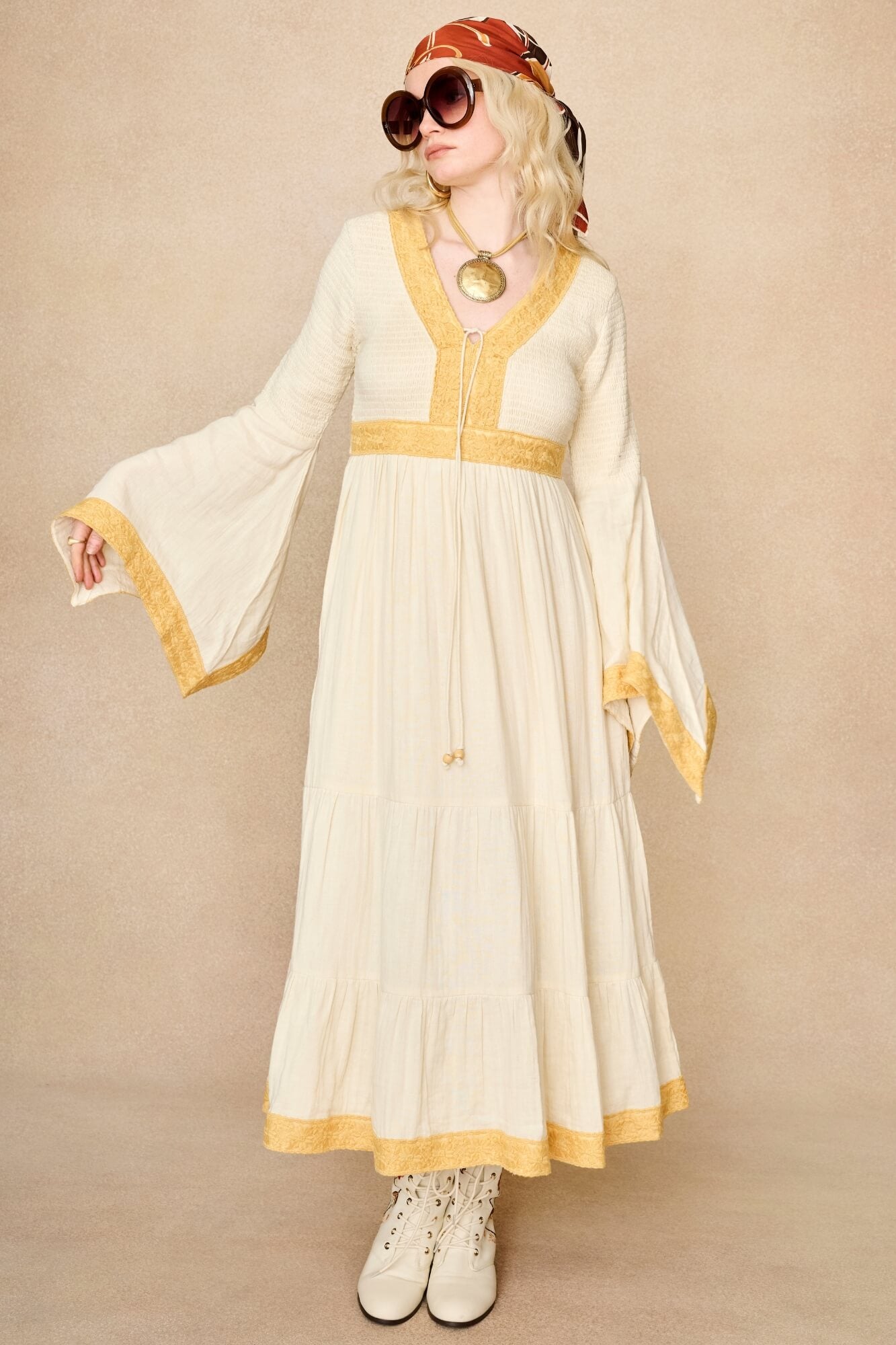 Model wearing 70s cream long sleeve maxi dress with lace-up Penny Lane boots by The Hippie Shake, front view