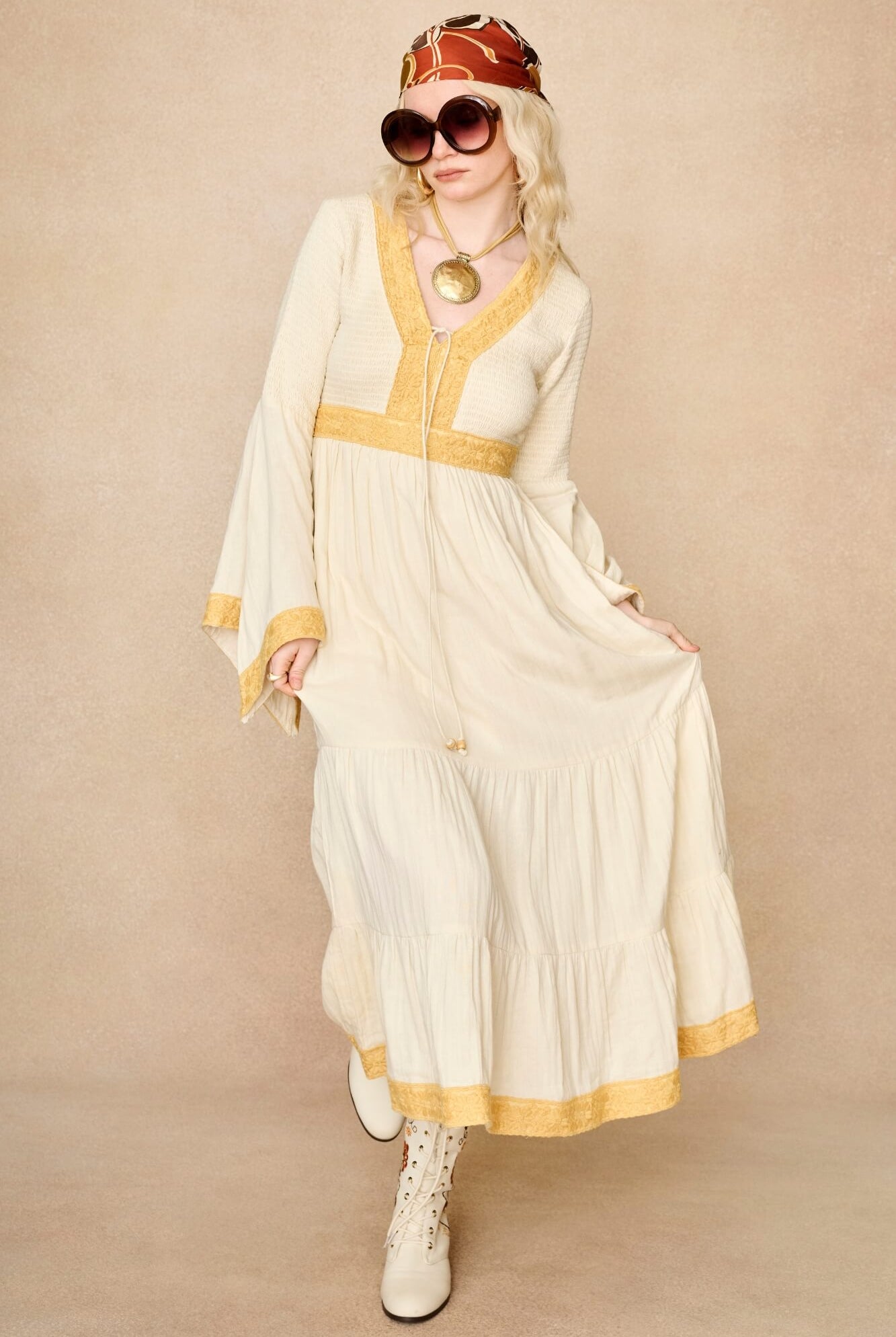 Model wearing 70s cream long sleeve maxi dress with lace-up Penny Lane boots by The Hippie Shake, front view