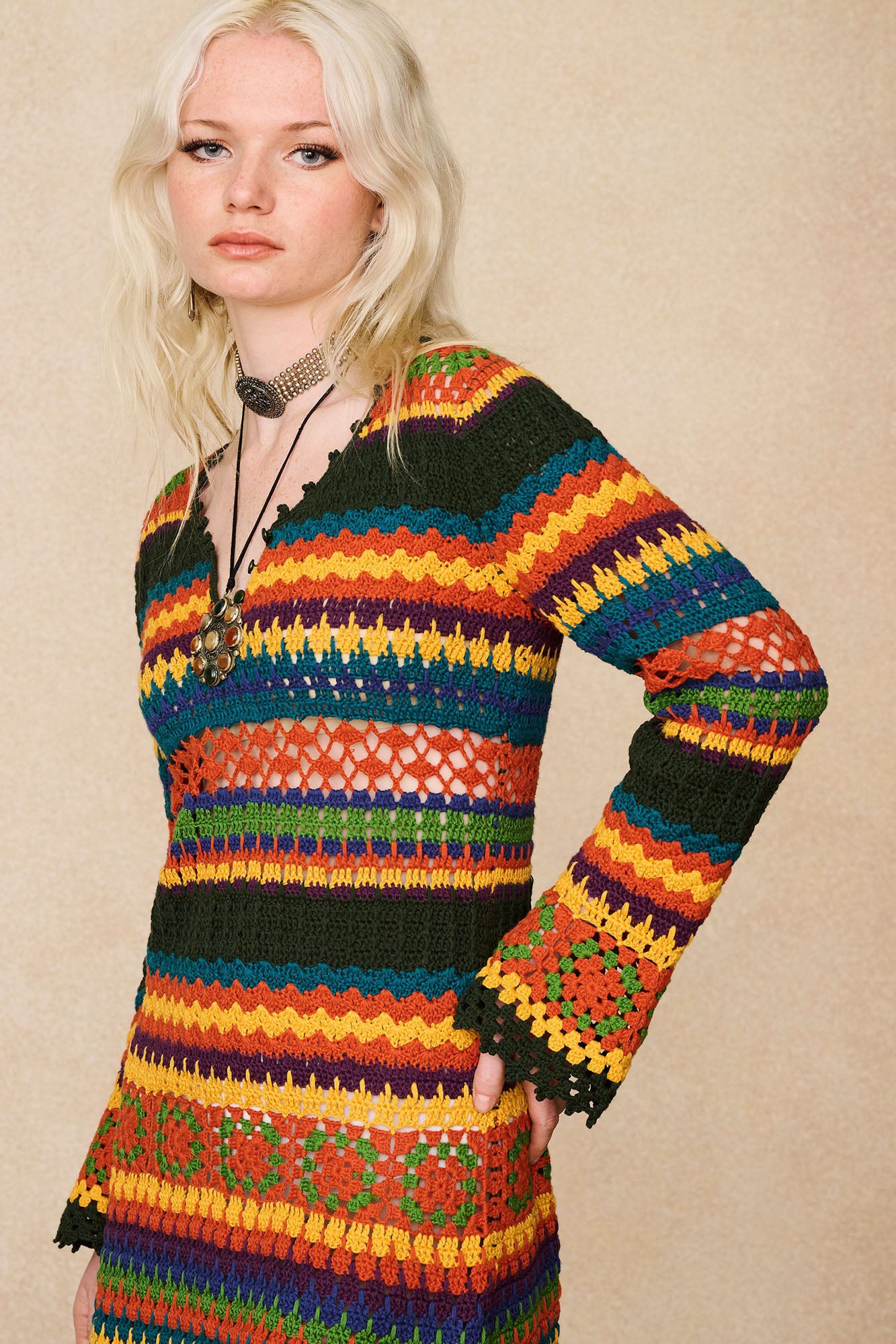 Side view of The Hippie Shake's 70s inspired multicolour striped crochet mini dress featuring flared sleeves.