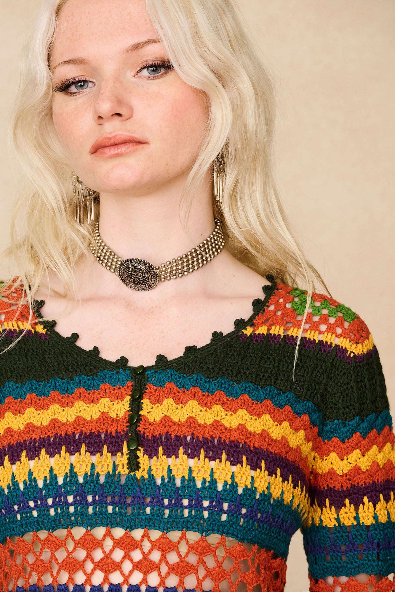 Close-up of The Hippie Shake's crochet dream mini dress, buttoned up and worn with a statement neck piece.
