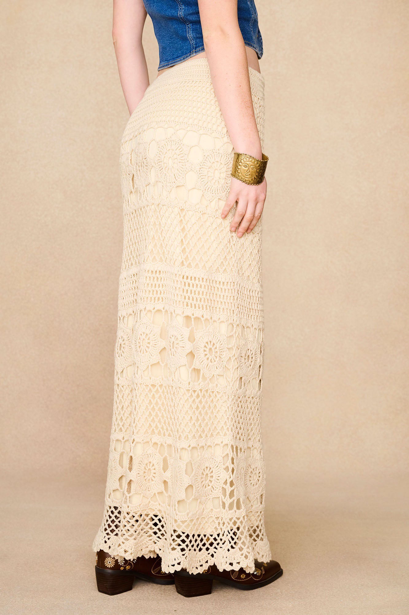 Side view of The Hippie Shake's cream crochet maxi skirt highlighting fitted shape and bold crochet textures.