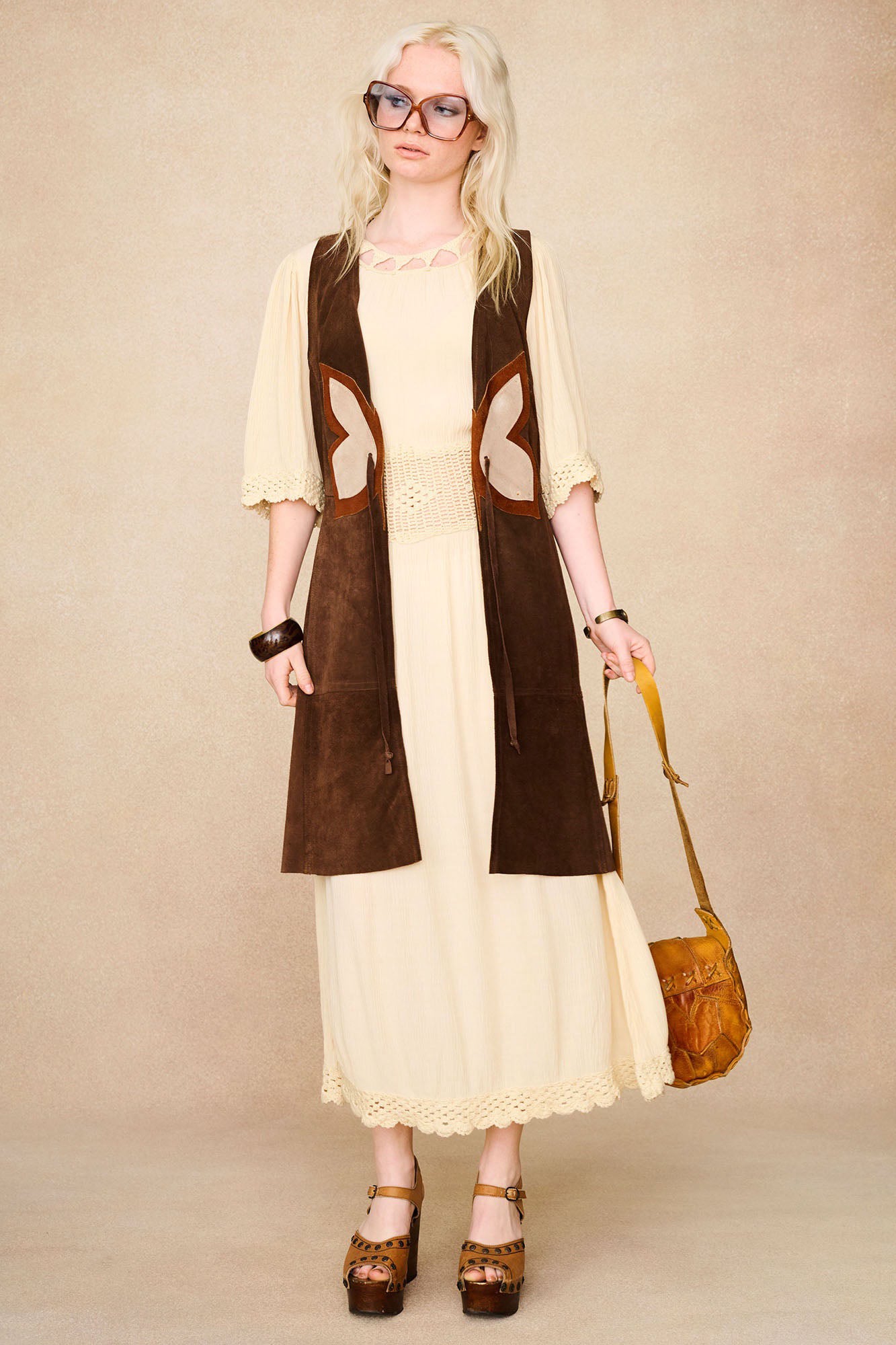 Model wearing The Hippie Shake's cream crochet midi dress with butterfly suede waistcoat.