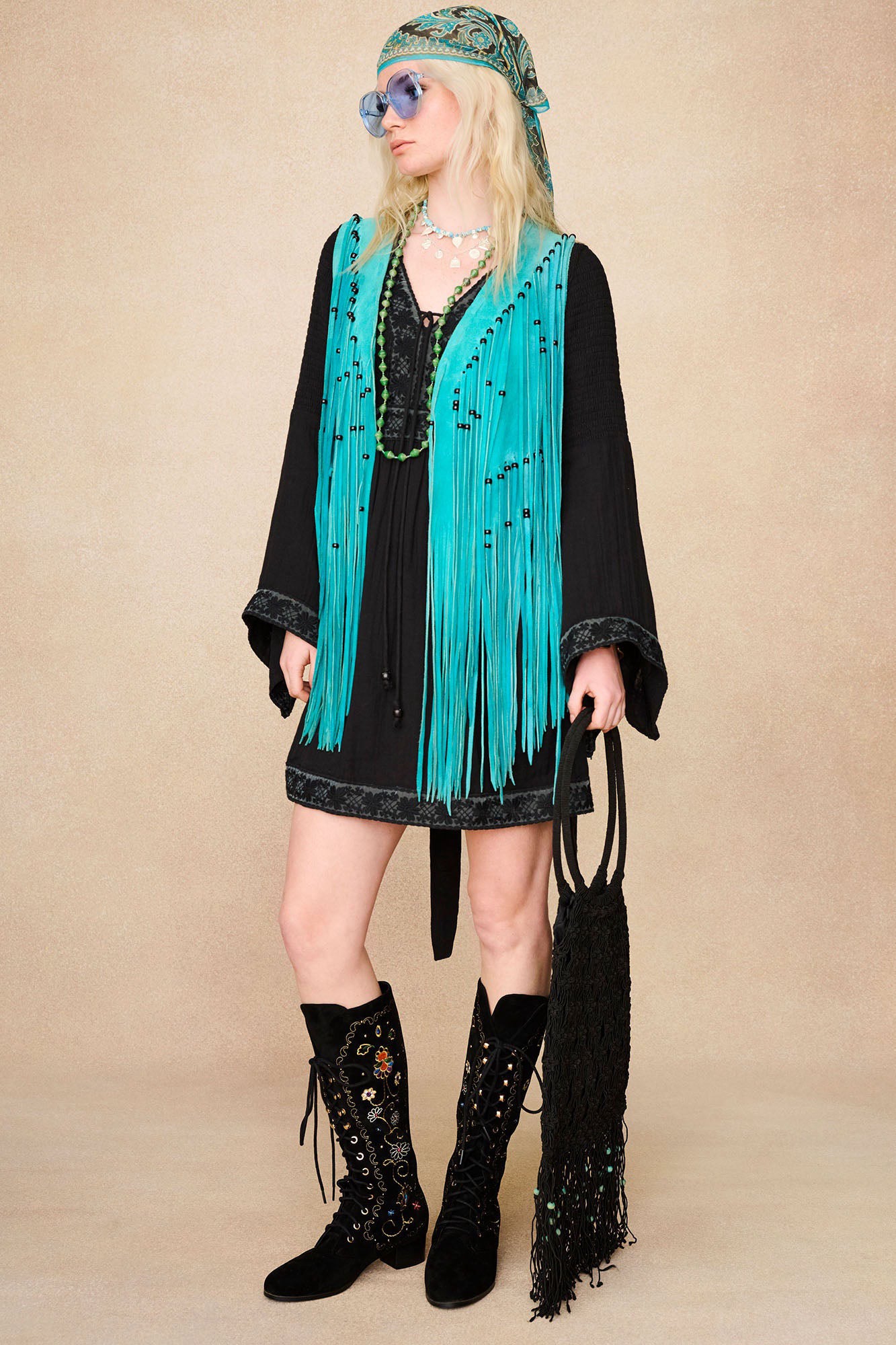 Model wearing The Hippie Shake's black mini dress with lace trim styled with our black embroidered boots and a blue tassel waistcoat.