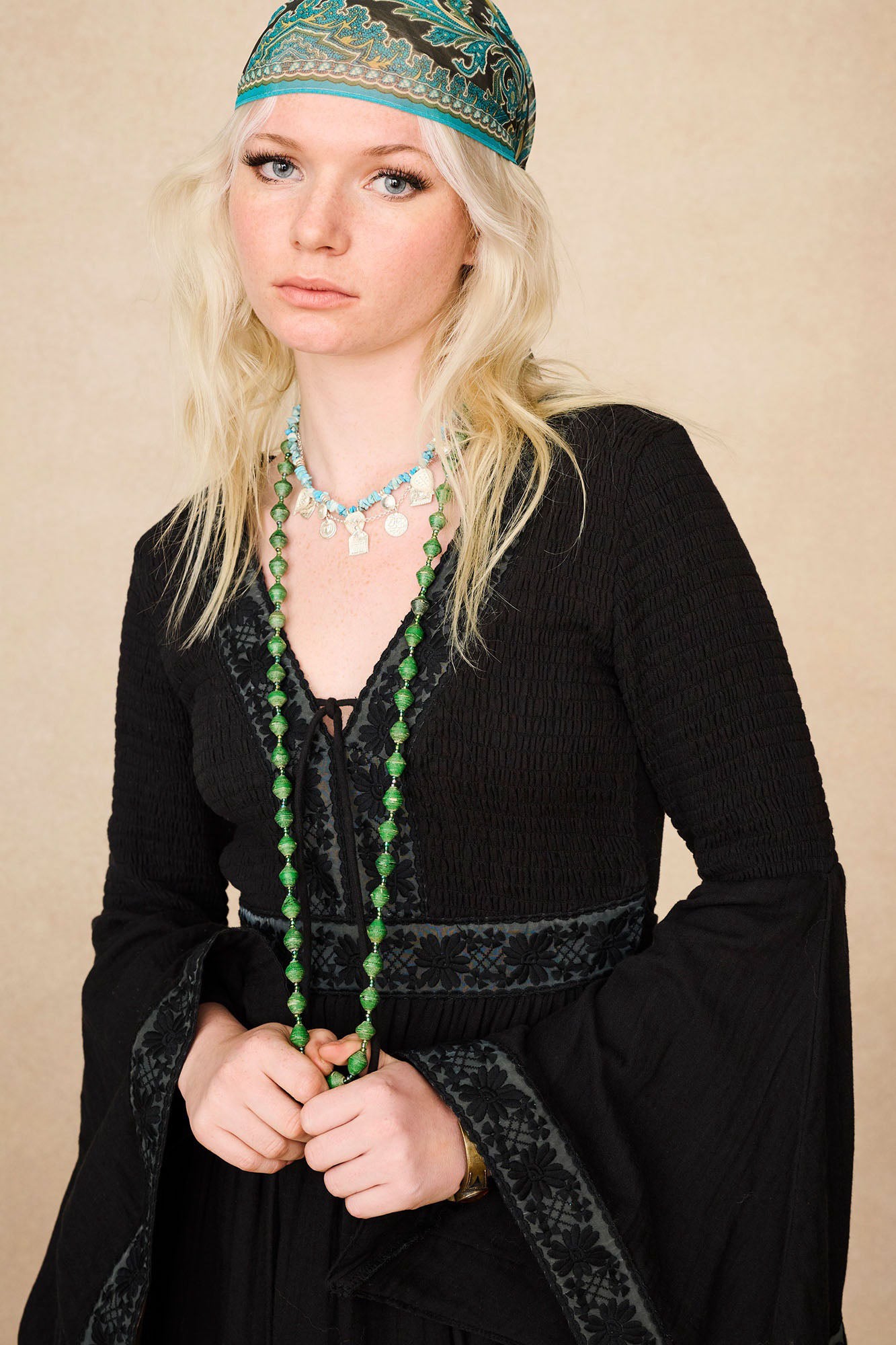 Close-up of model wearing The Hippie Shake's black vintage mini dress with lace trim and flared flowy sleeves.