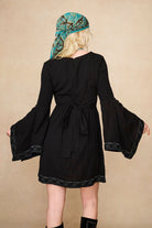 The Hippie Shake's black mini dress with lace trim and flared 70s style flowy sleeves shown from behind.