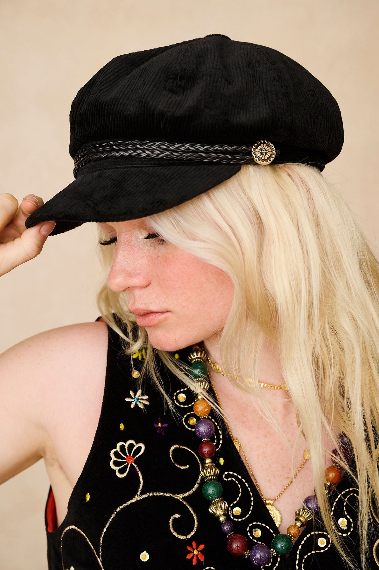 The Hippie Shake's corduroy baker hat shown in side profile worn with our vintage black velvet embroidered waistcoat.