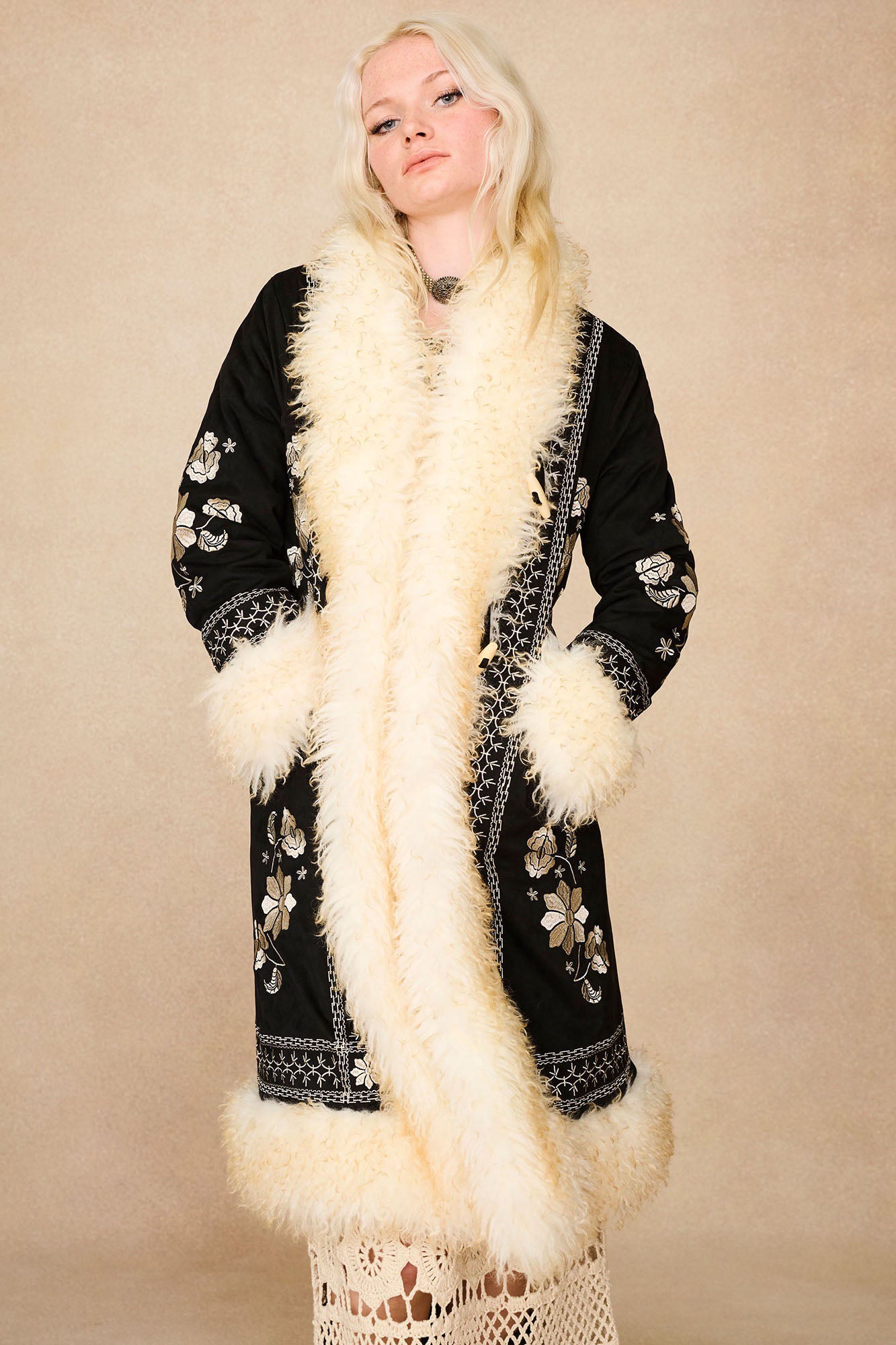Model wearing the Hippie Shake's black afghan coat with hands in pockets, accentuating the off-white shaggy faux fur trims.