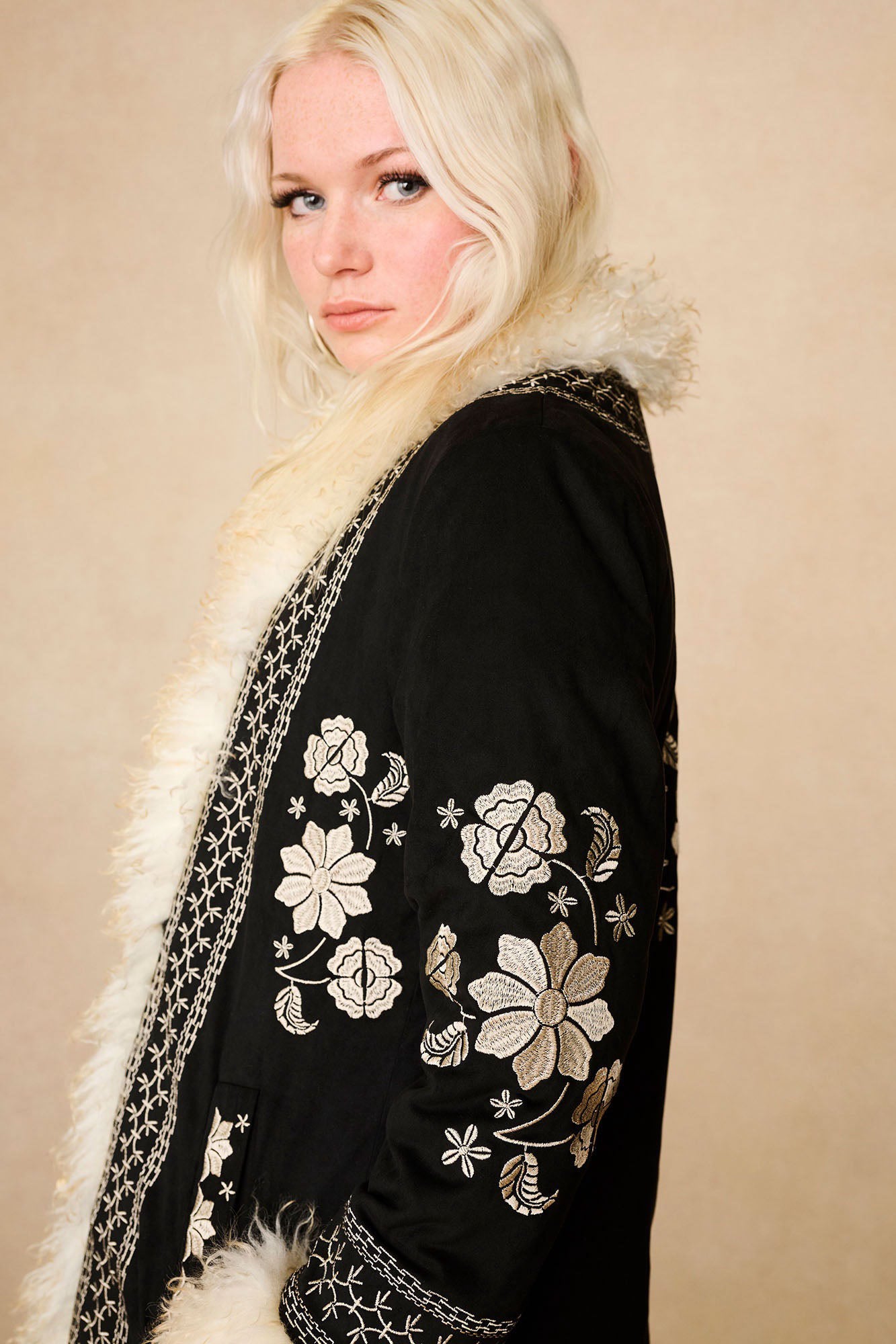 Side profile of The Hippie Shake's vintage inspired black afghan coat featuring the intricate embroidery down the sleeve.