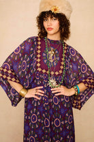 Model wears a 70s style bohemian maxi dress in a printed purple fabric with hand embroidery - close up
