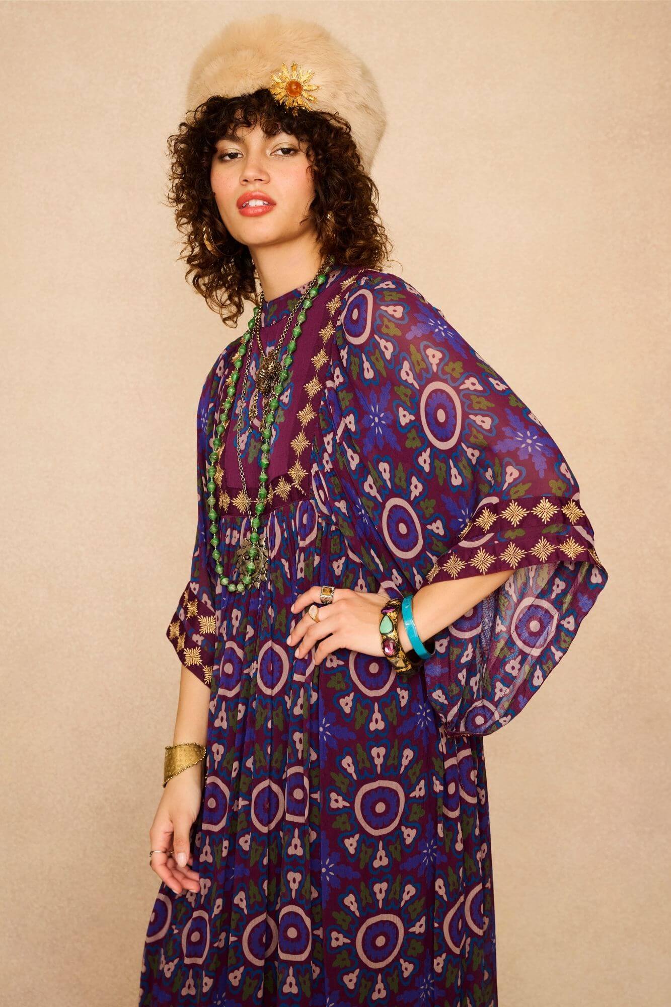 Model wearing a 70s style bohemian maxi dress in a printed purple fabric with hand embroidery - side view