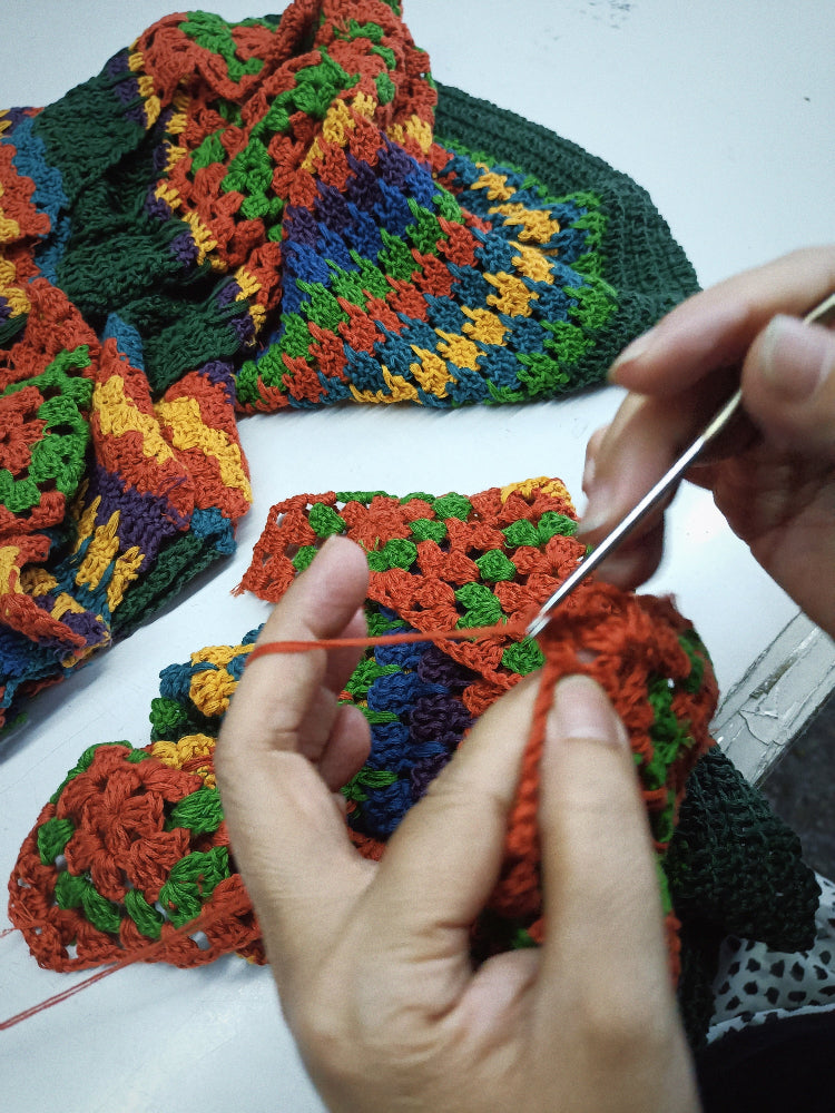 A close up of hands making The Hippie Shake's colourful crochet dress