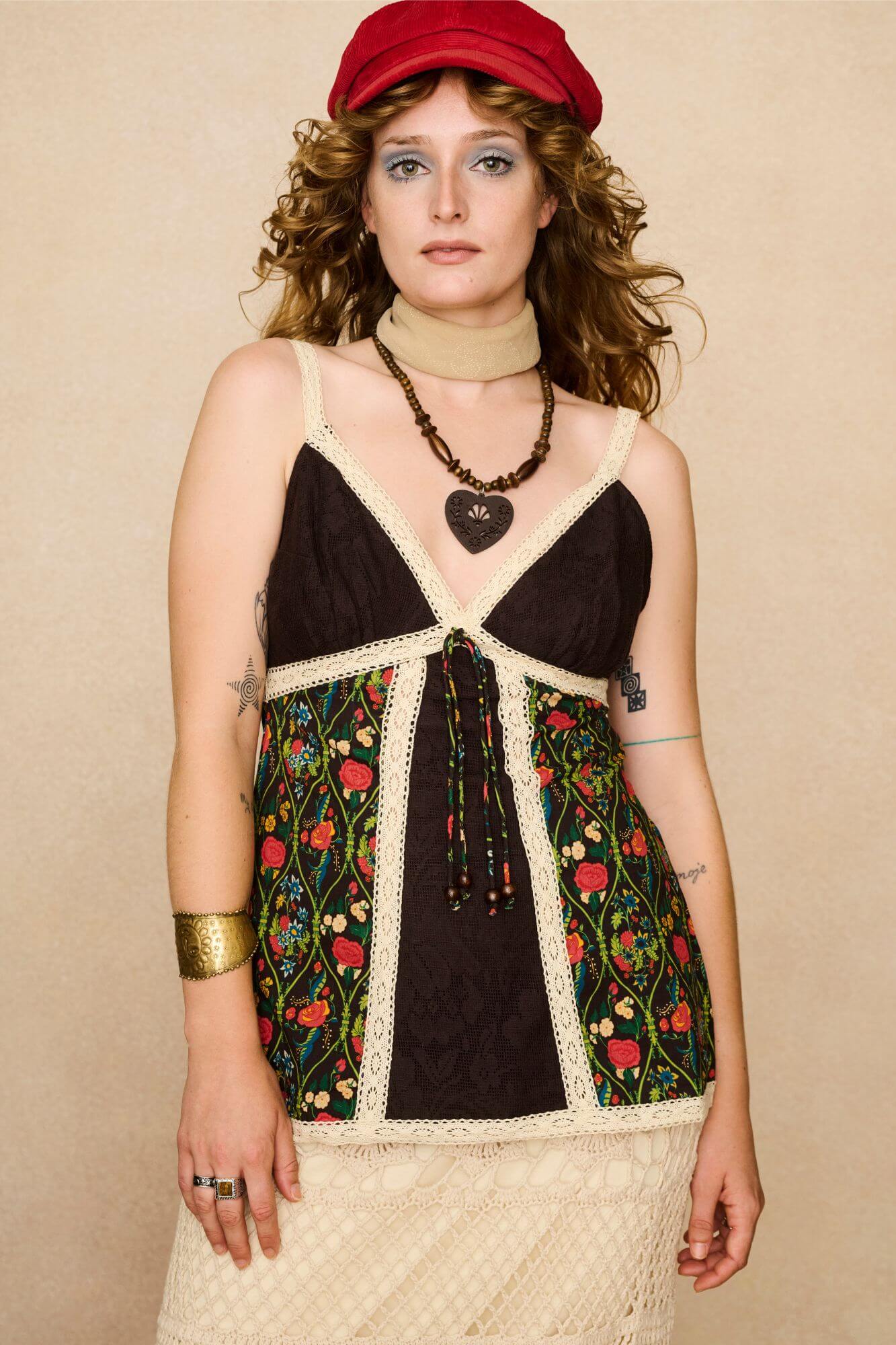 Model wearing a strappy 70s style floral top with against a beige background - front view
