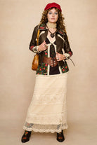 Model wearing a strappy 70s style floral top with against a beige background - outfit with skirt