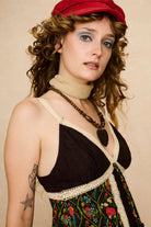 Model wearing a strappy 70s style floral top with against a beige background - close up front view