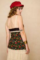 Model wearing a strappy 70s style floral top with against a beige background - back view