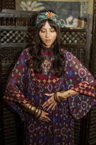 Model dancing wearing a 70s style bohemian maxi dress in a printed purple fabric with hand embroidery - close up