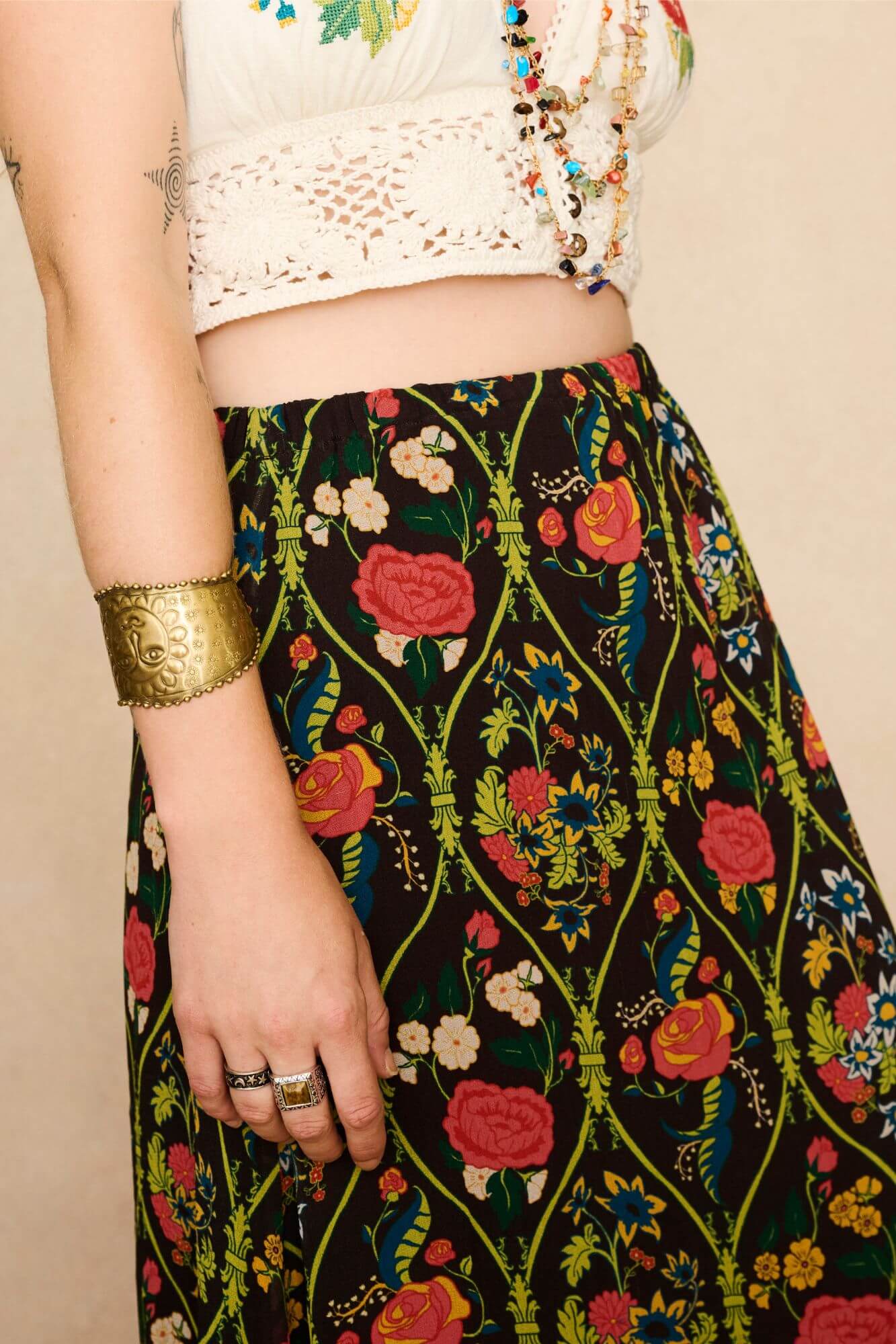 Model wearing a long 70s style floral skirt and white top with a beige background - print close up