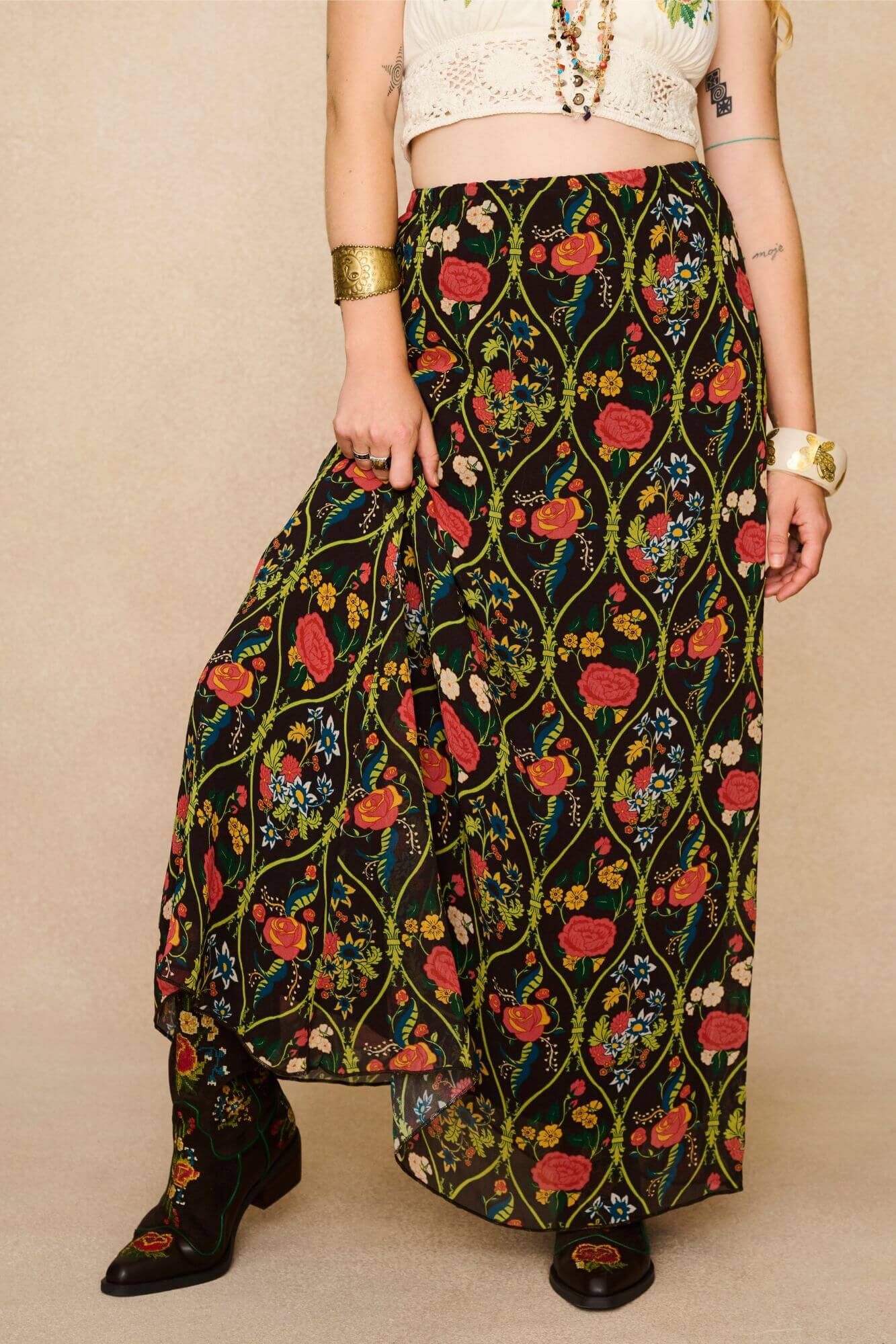 Model wearing a long 70s style floral skirt and white top with a beige background - close up