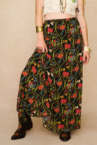 Model wearing a long 70s style floral skirt and white top with a beige background - close up