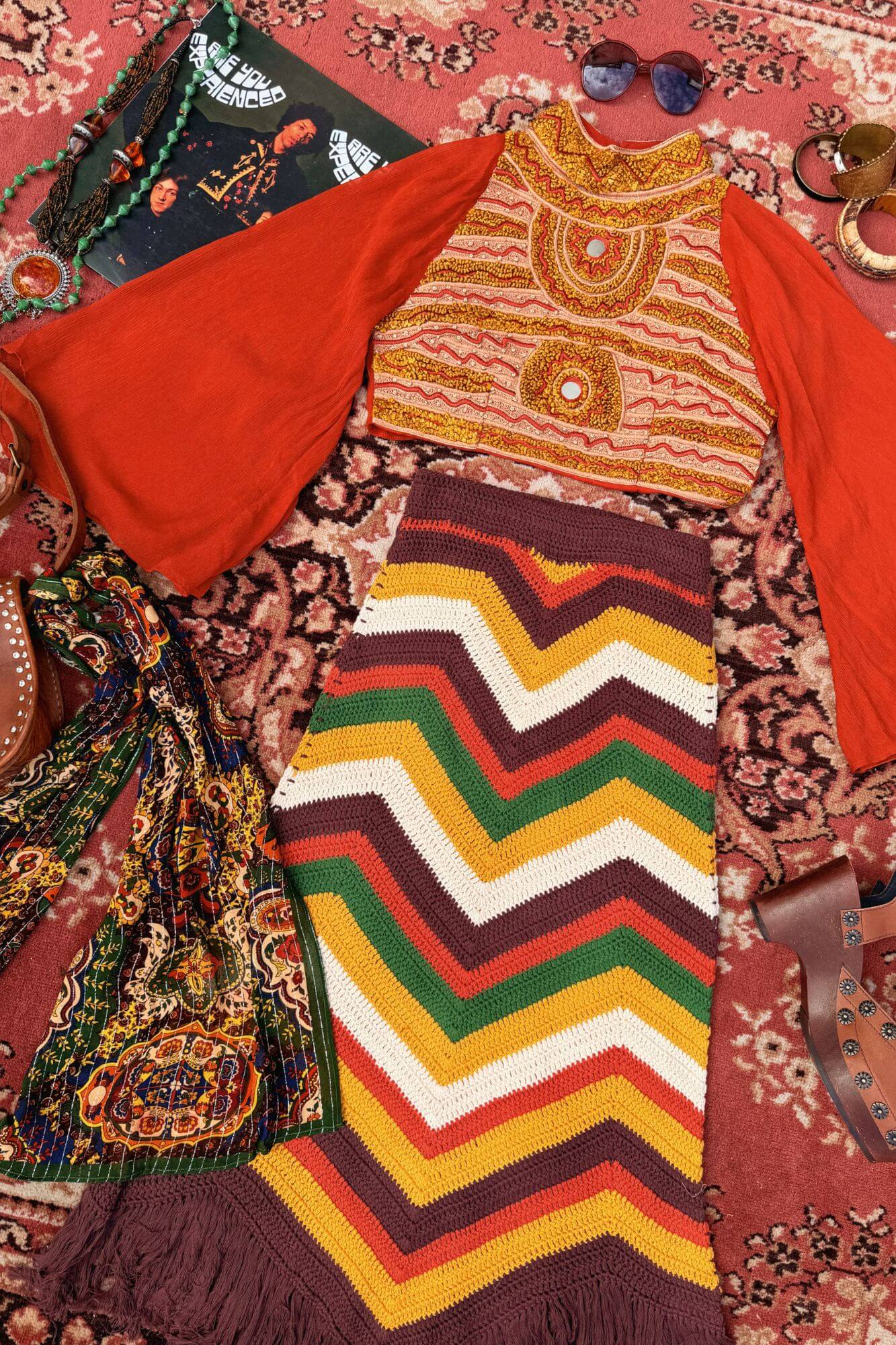 Flat lay of 70s style fashion and crochet garments on a vintage carpet