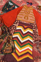 Flat lay of 70s style fashion and crochet garments on a vintage carpet