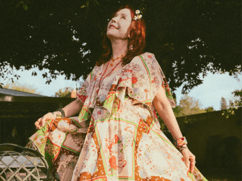Pamela in The Hippie Shake's handkerchief print dress standing outdoors with trees