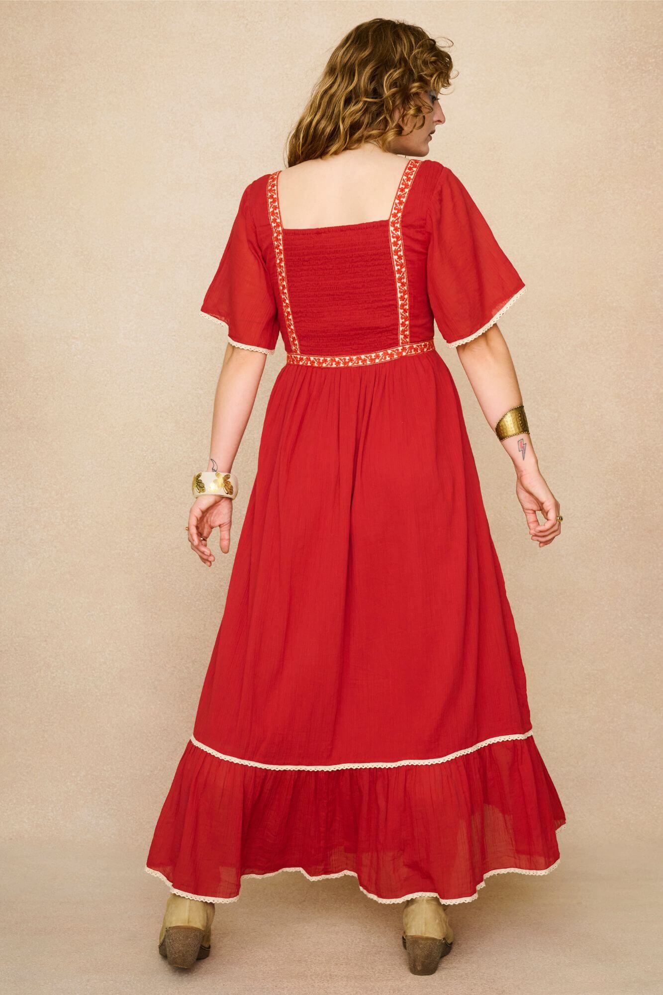 Model wearing a red floaty maxi dress with embroidered details - back view